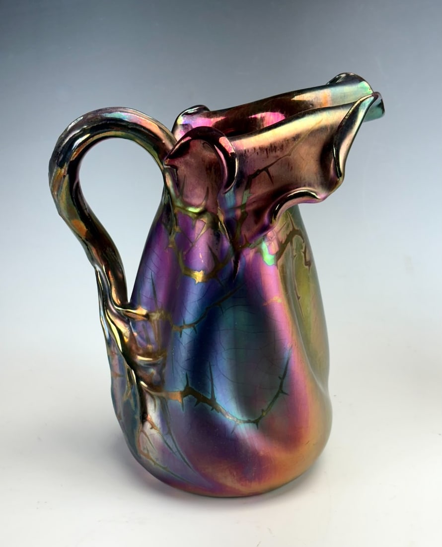 Pierre Perret French Iridescent Feuillages Pitcher: Circa 1900, a ceramic Feuillages pitcher with red, silver and gold iridescence with iris and foliage decoration and tree branch handle. Pierre Perrot worked for Jerome Massier at Villauris, France. We