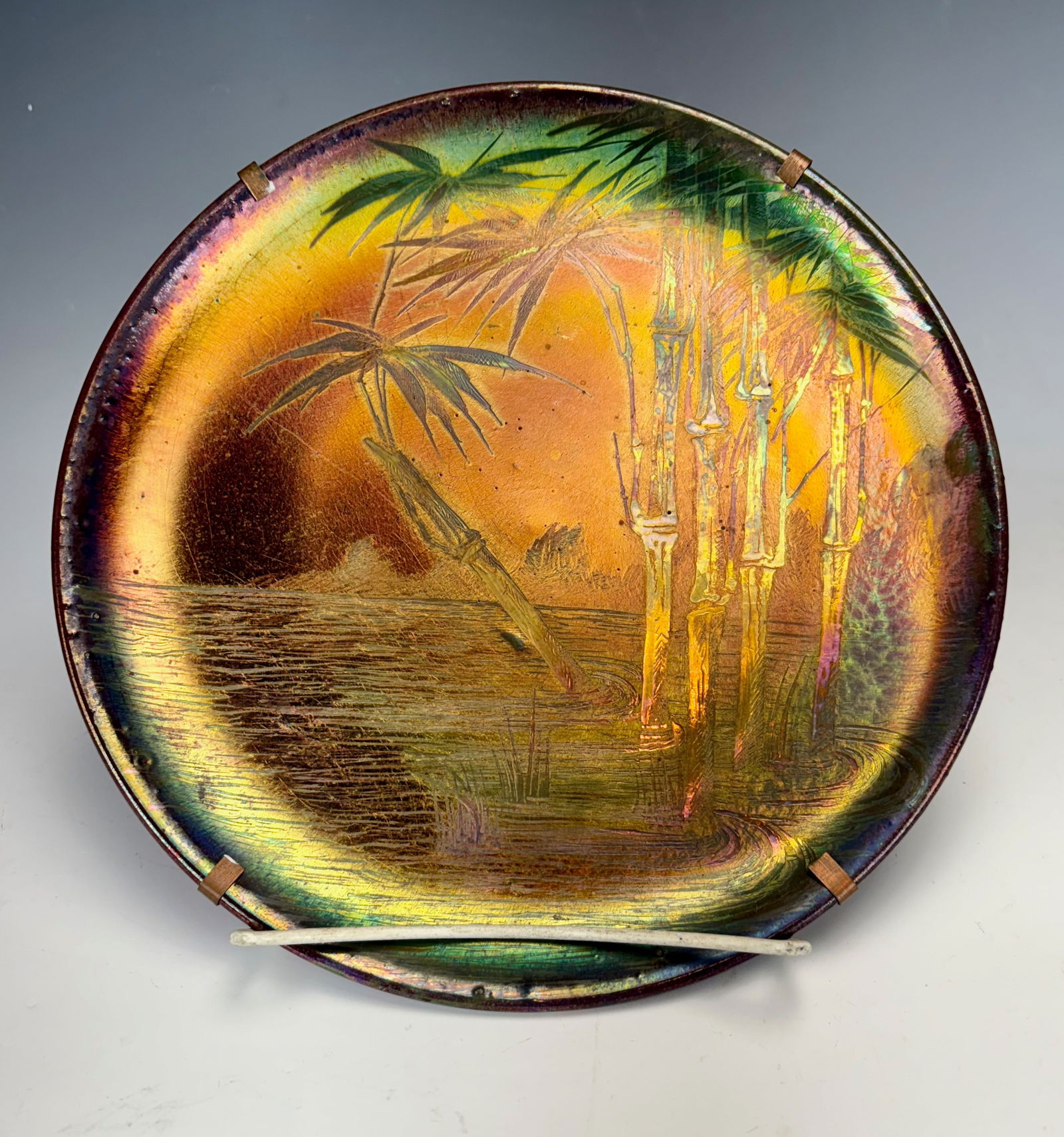 Pierre Perret French Iridescent Plate w Palms: Circa 1900, Pierre Perret worked for Jerome Massier at Vallauris, France. Ceramic plate has rich multicolor iridescence and palm and sea decoration, signed on back "P Perret, Vallauris", retains origi