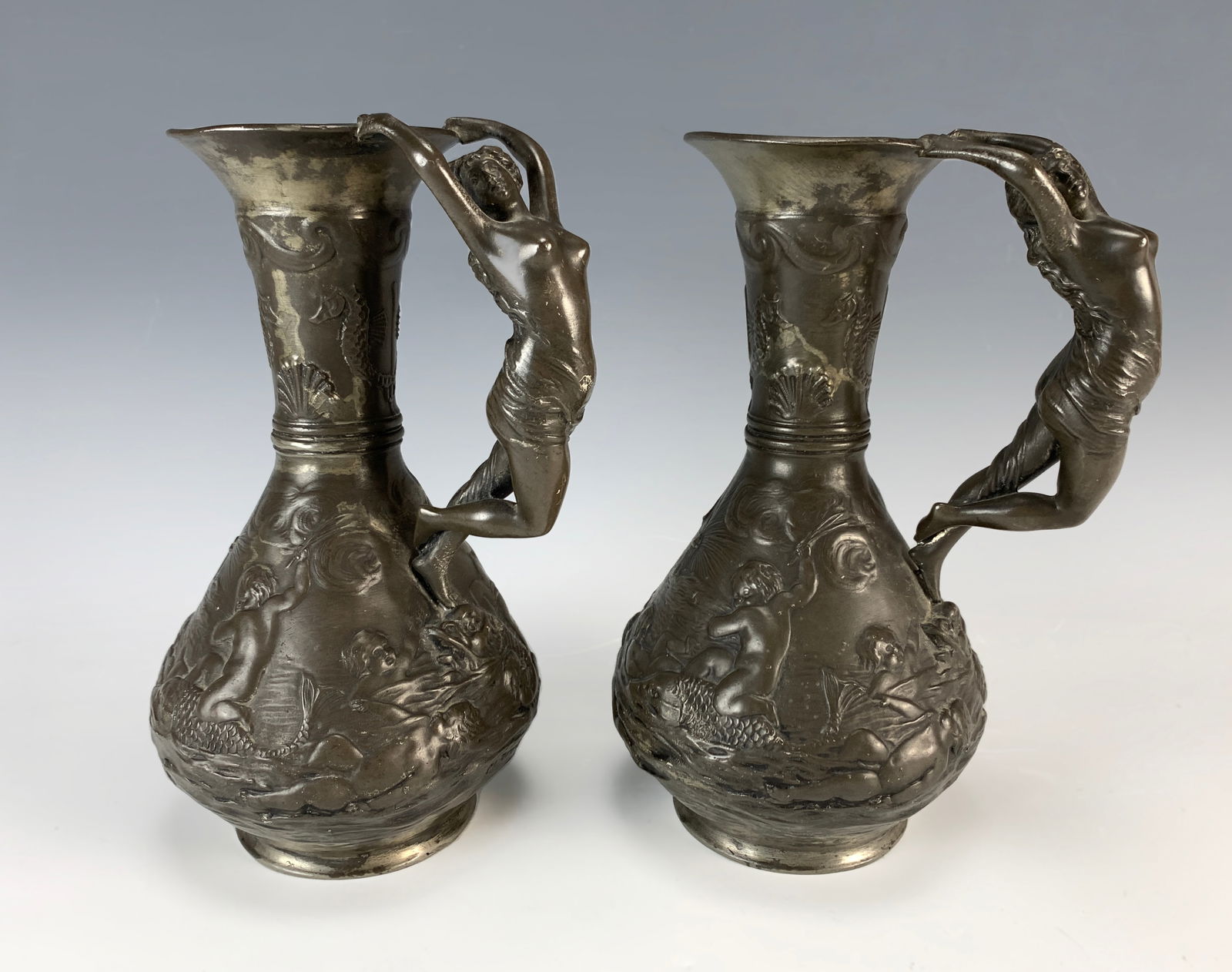 Antique Art Nouveau Ewer with Nude Handles Signed: Circa 1890. Signed "Ch. Perron Etain Garanti Paris". A superb art nouveau ewer in patinated pewter with relief scene having dolphins and putti, seahorses at the top, and handle with semi-nude maidens.
