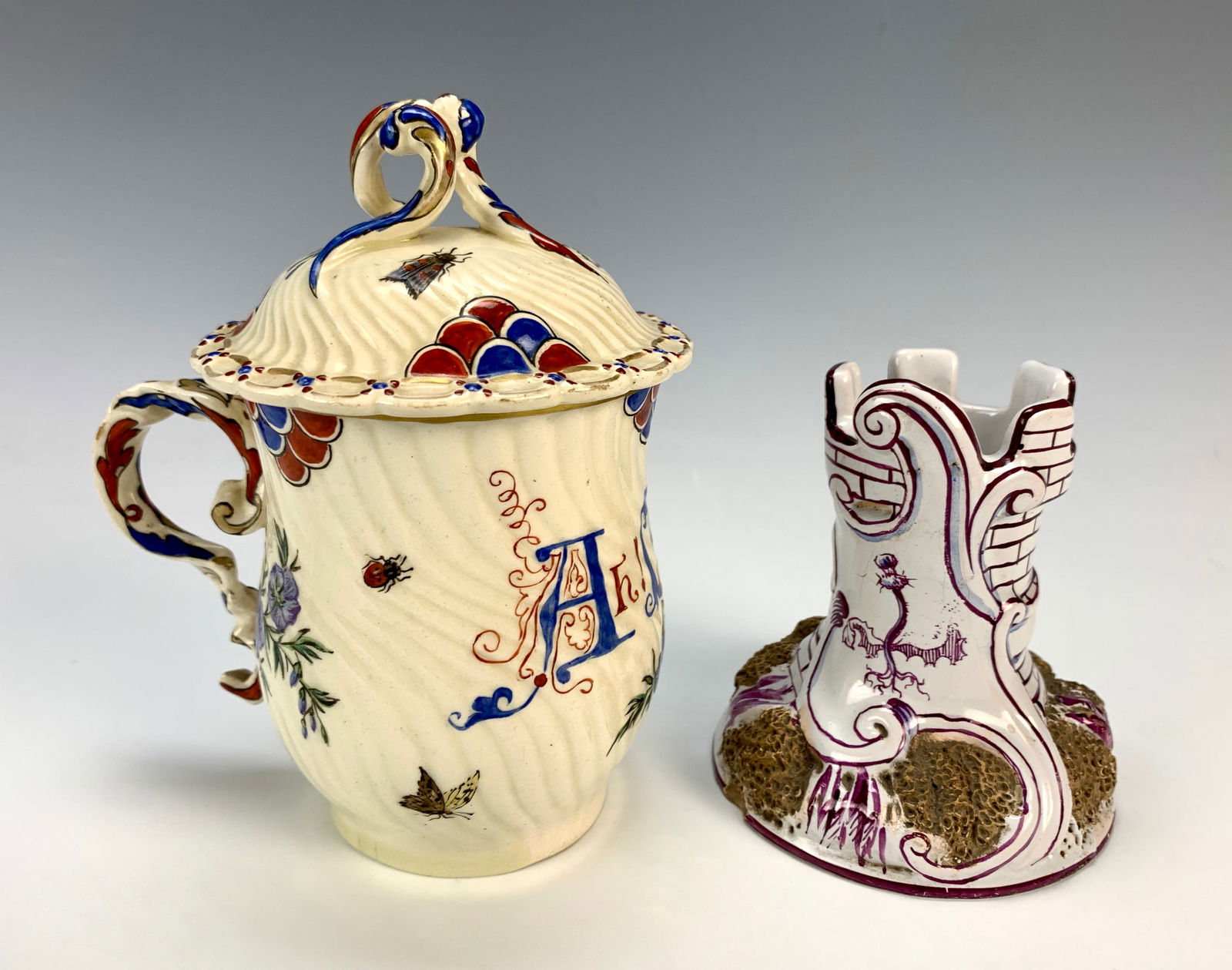 Pr Galle Pottery Items Covered Cup & Candlestick: Circa 1900. a handled covered cup decorated with red and blue decor, a shield with a crown and words "Ah! Fleureux temps que ce stoic", all over a cream body. Signed on bottom "Galle, Nancy" and a pot