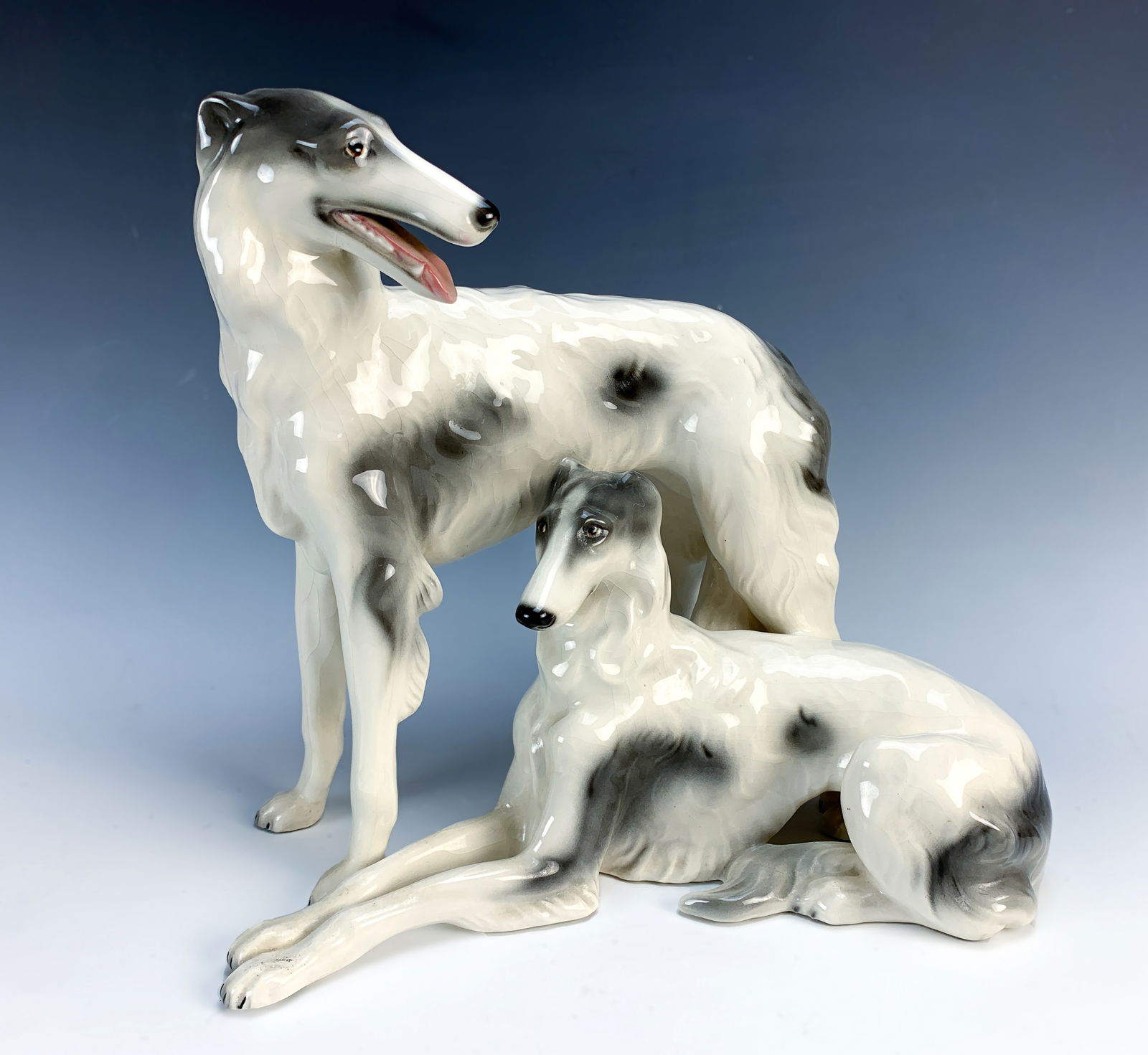 Goldscheider 2 Russian Wolfhound Dog Figurines: Fine porcelain figurine of 2 Russian wolfhounds signed with Goldscheider mark, made in Austria and hand decorated. Marked "26", "7571", "66". Very good condition, tallest 12" x 13" wide.