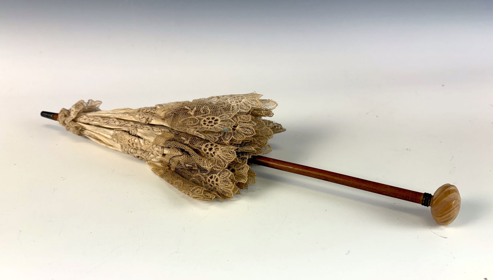 Antique Doll Parasol with Lace: An antique doll parasol with lace detailing, charming and delicate in presentation. 16” long. Folded up it looks great, but it has issues when opened.