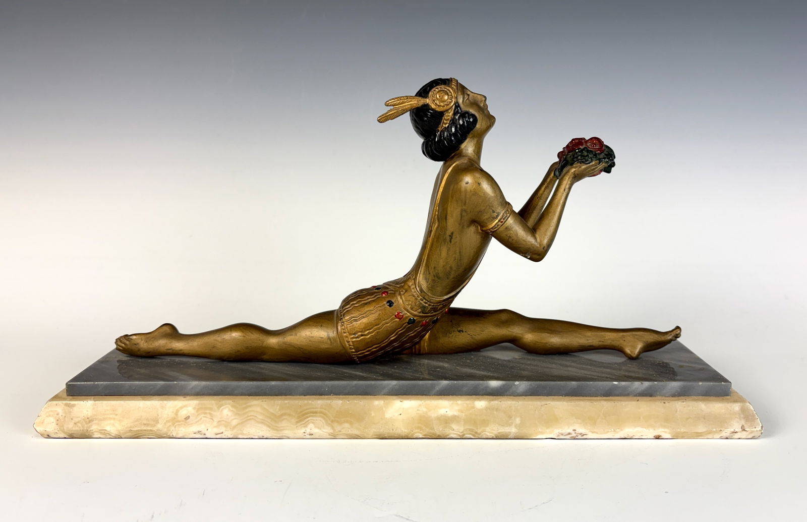 Art Deco Dancer Sculpture w Bouquet of Flowers: A patinated metal figure depicting a dancer holding a bouquet of flowers, mounted atop a marble and onyx stepped base. The piece retains an applied foundry seal and dates to the 1920s. 8” tall �