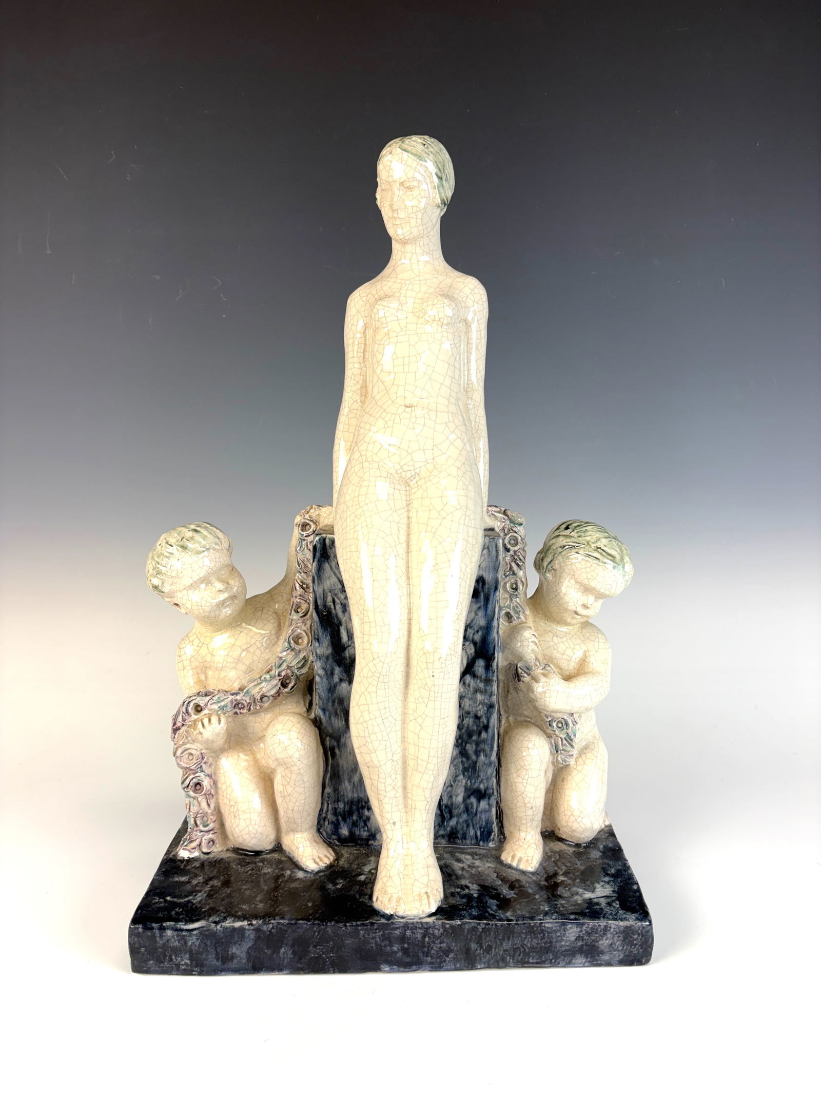 Fernand Guignier Seated Woman Art Deco Figurine: Fernand Guignier (1902–1972) circa 1920s, signed on the verso, Art Deco figurine depicting a nude lady seated on a wall, surrounded by two playful putti. 17.5” tall × 10.5” wide × 5.5&