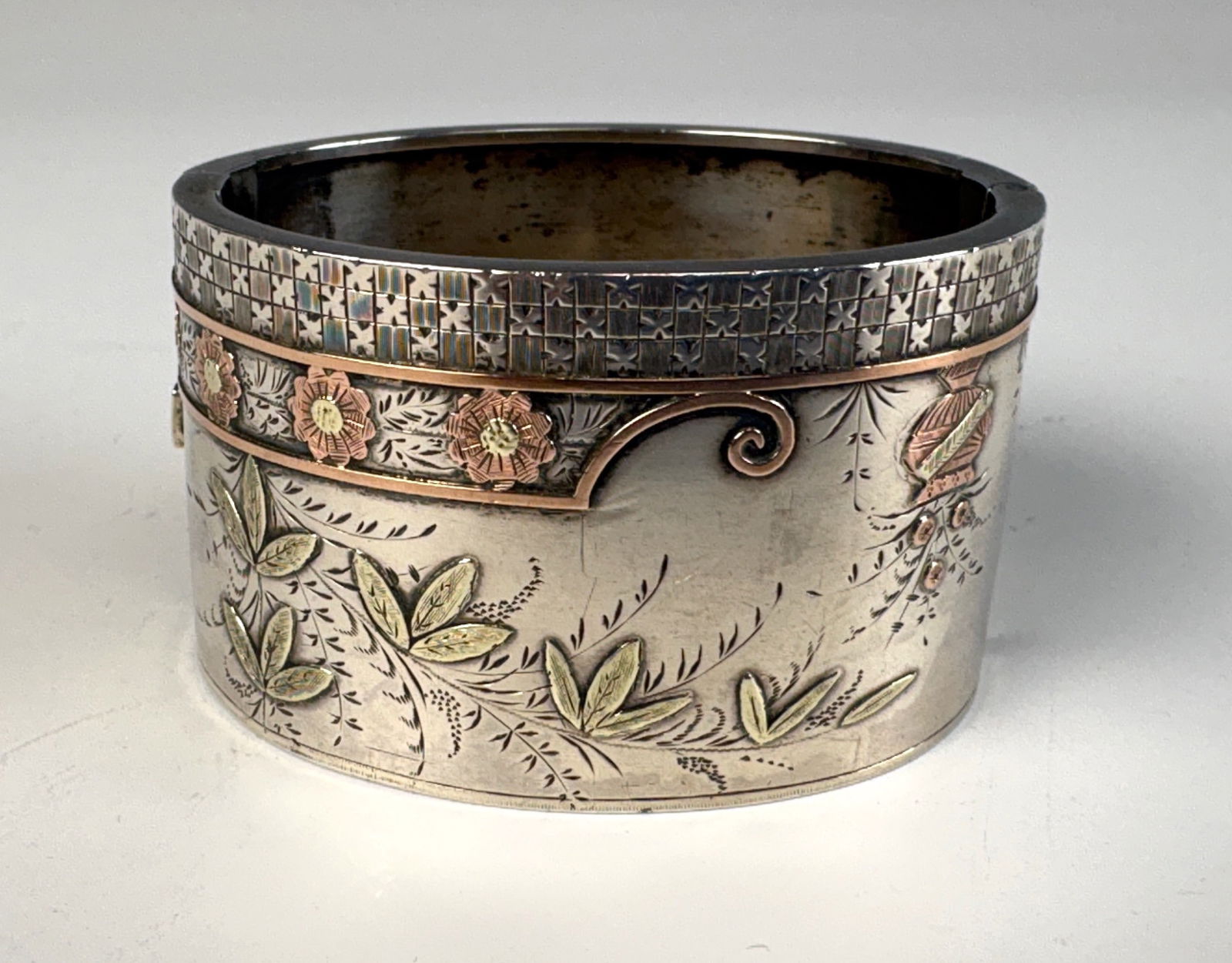 Sterling Silver Mixed Metal Cuff Bracelet: A wide cuff bracelet made of sterling silver and mixed metals, decorated with copper and gold flowers and leaves, very good condition other than minor dents on underside, Width 1.5", 2.22” inner