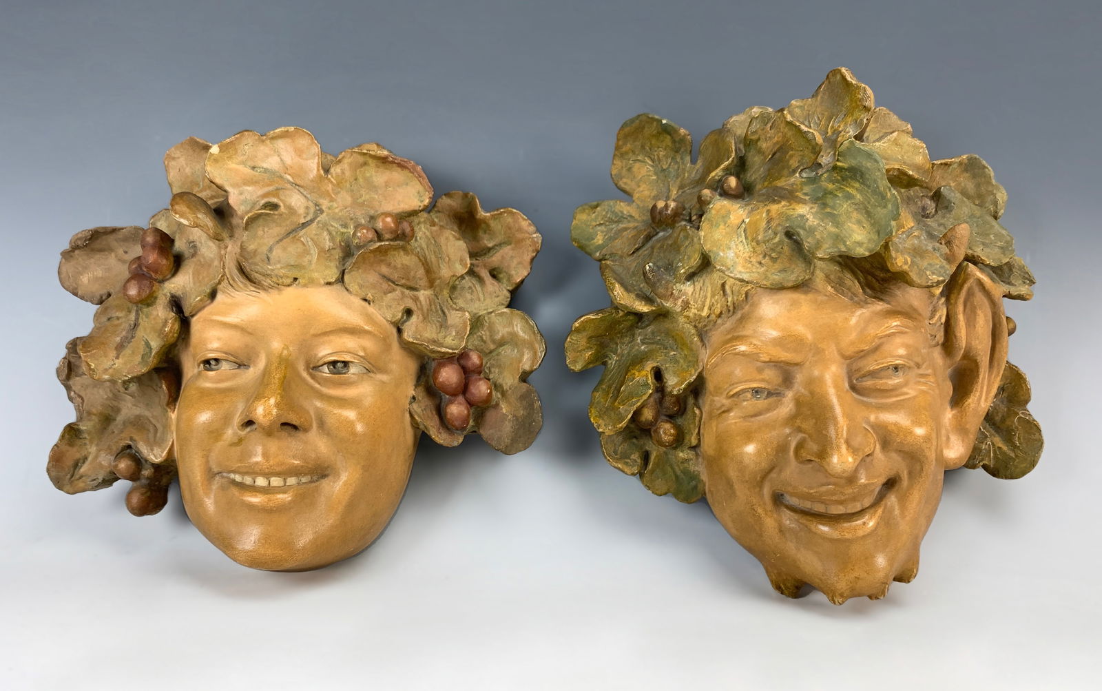 Goldscheider "Bacchus & Satyr" Masks c.1900: Antonin Larroux (1859-1913) Pair of polychrome terra cotta masks by sculptor Antonin Larroux. The masks are of Bacchus and Satyr. While both are signed, only one has the Goldscheider stamp and numbers
