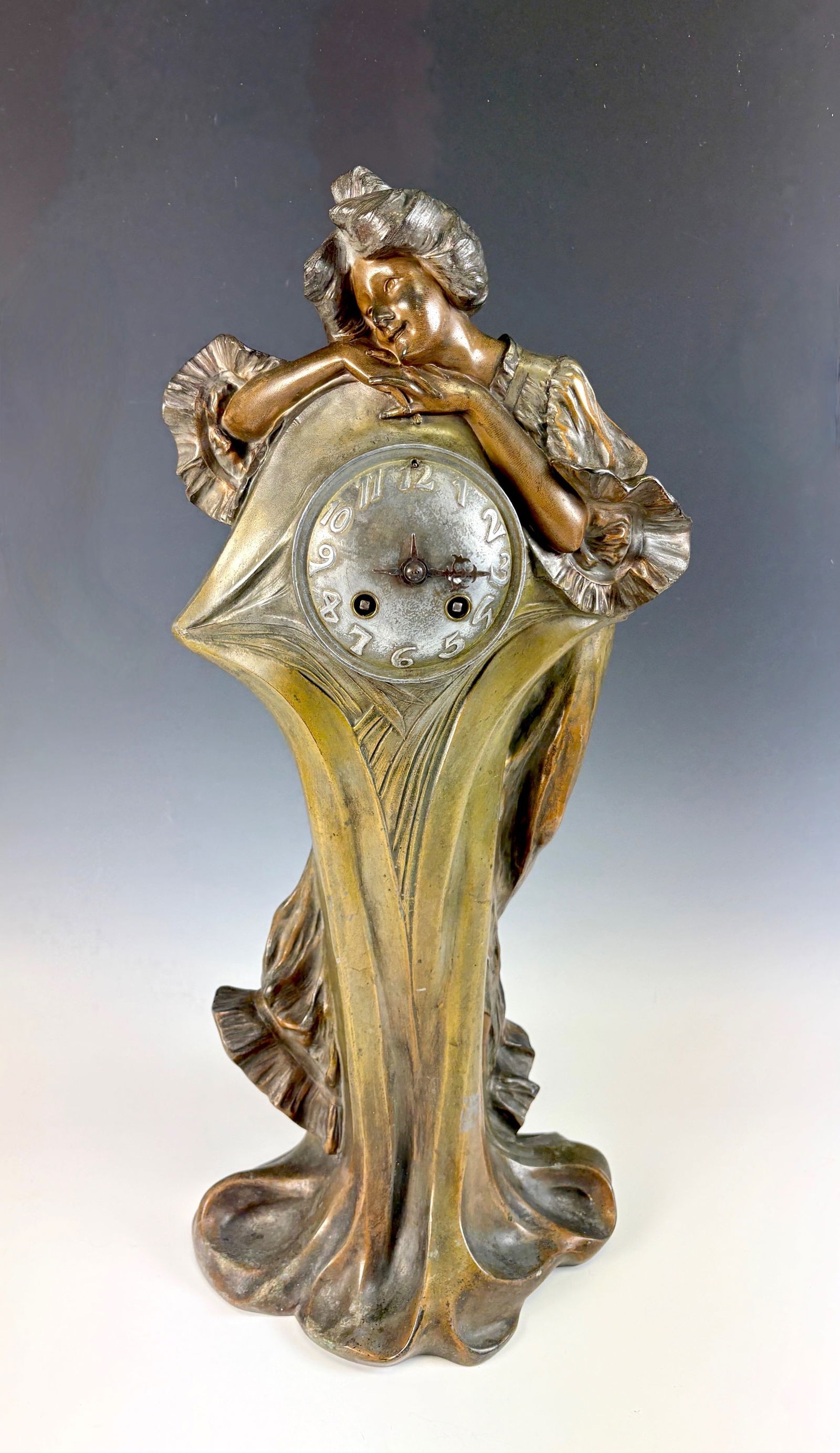 Art Nouveau Figural Lady Clock Signed “Flora: An Art Nouveau figural clock depicting a lady in patinated metal, signed F. (Francesco) Flora. The clock movement is marked "A. Junghans, Wurttemberg Clock Factory." (includes pendulum and key). In go