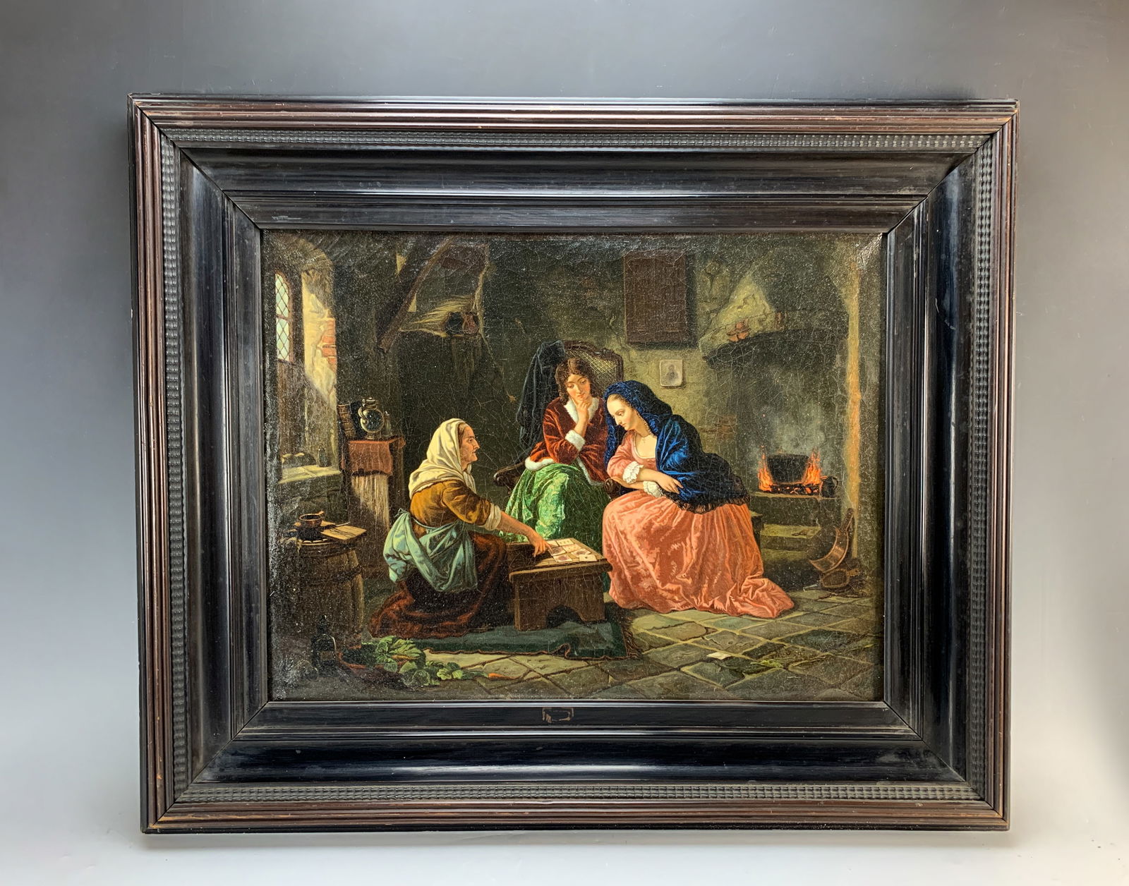 19th Century "Fortune Teller" Oil On Canvas: Quality oil on canvas painting depicting two young women being told their fortune by the fireside. Signed with monogram, mounted in its original mahogany frame. Sight 16" tall x 21" wide. With frame: