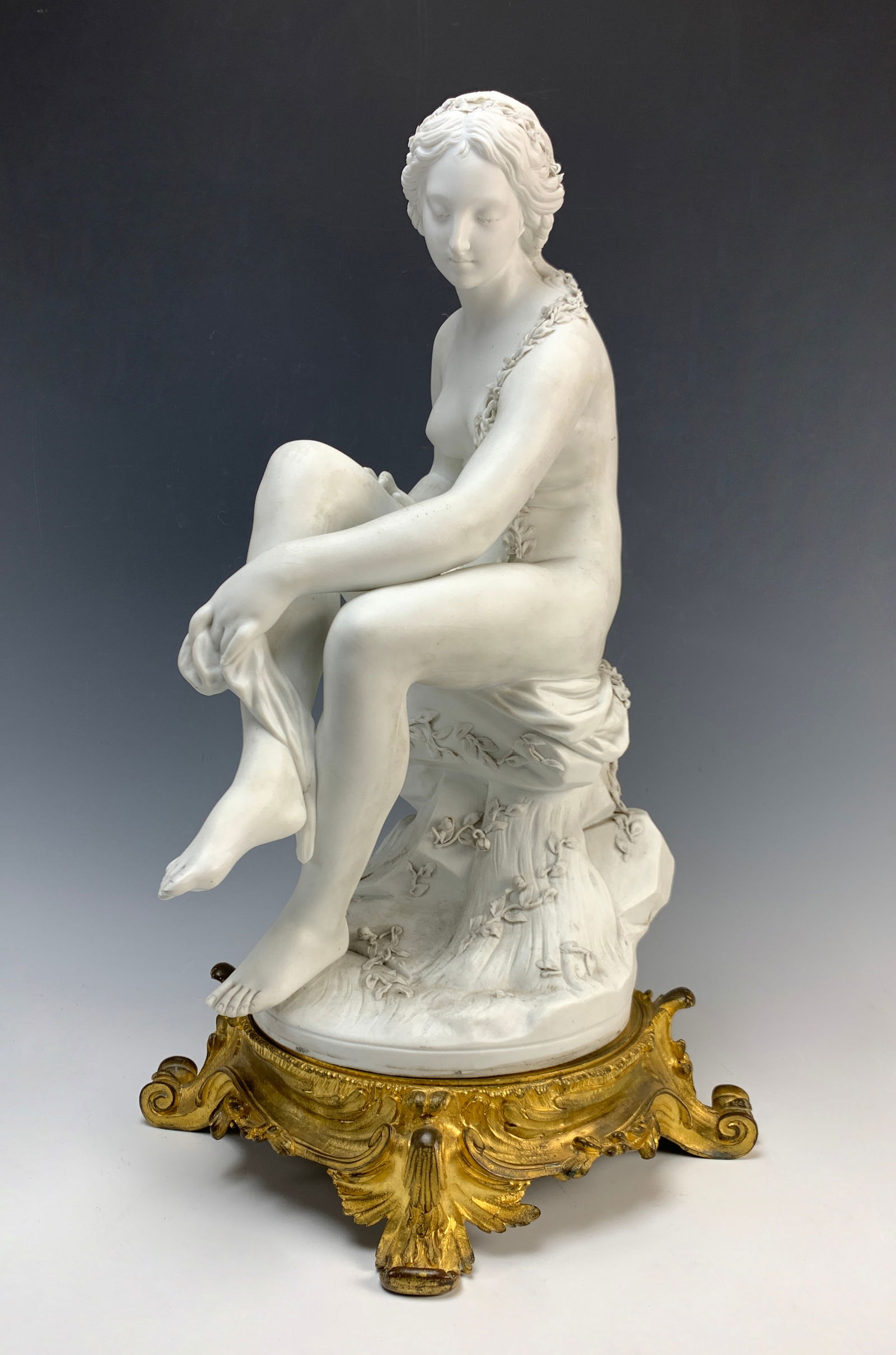 Sevres Bisque Porcelain Nude Seated Woman: Signed Sevres and artist signed seated nude white bisque figure on a woman seated on a French ornate gilt bronze base. Signed with Sevres interlaced LL and sculptor signed "J Feueheue?" Very good cond