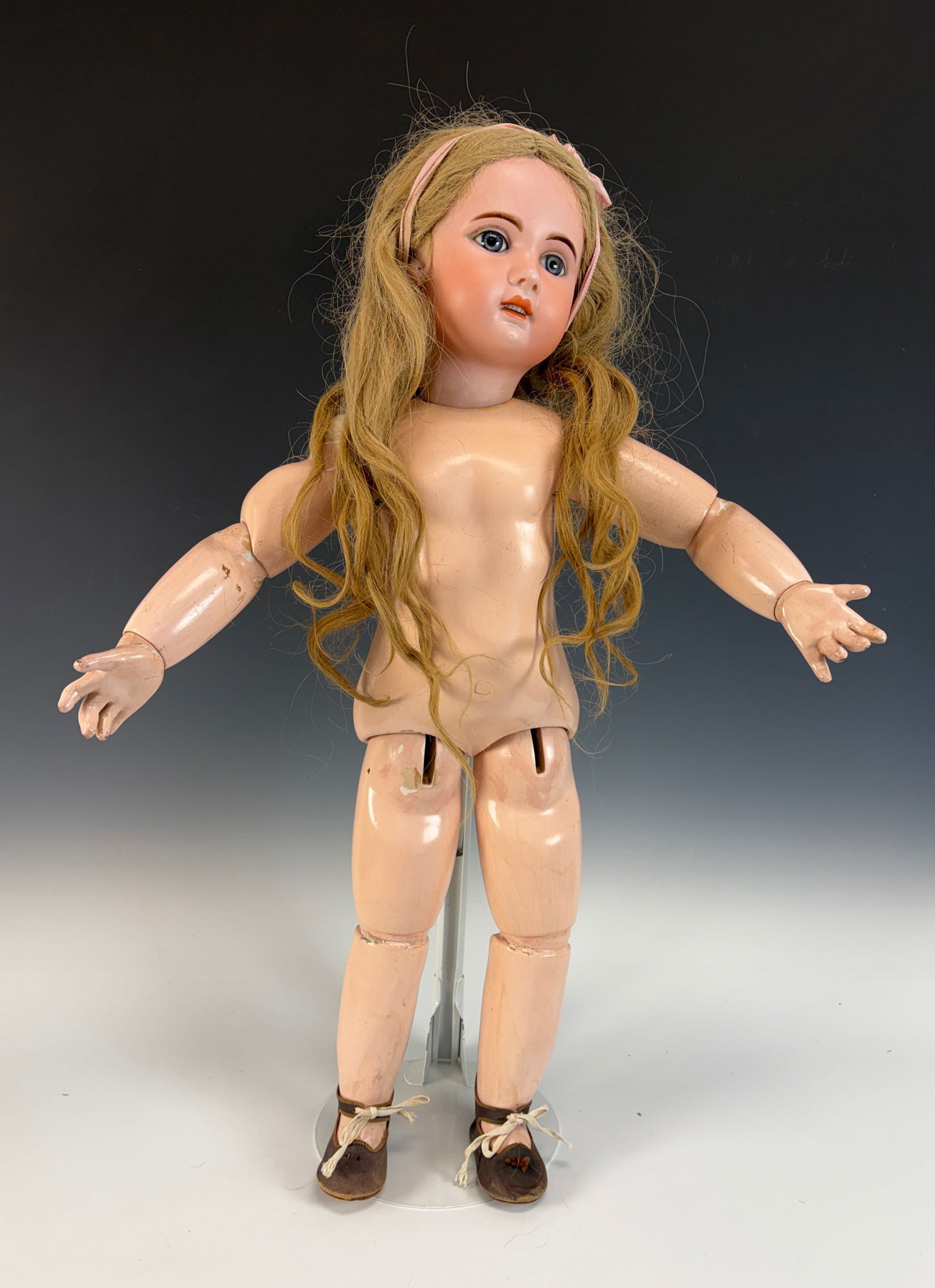 French Bisque Bébé by Jumeau, 1907: A French bisque socket-head doll by Jumeau, dated 1907, featuring an open mouth with teeth in the top, blue sulphur eyes, pierced ears, and an articulated body. The head is marked 1907 with a red twin