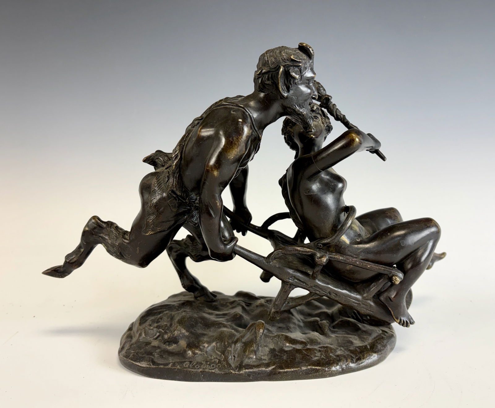 Bronze Satyr with Nude Lady by Clodion: Circa 1900, a fabulous bronze signed Clodion depicting a lively satyr pushing a nude lady seated in a wheelbarrow,. In very good condition, 11.5” wide × 9.75” tall × 6.5” deep.