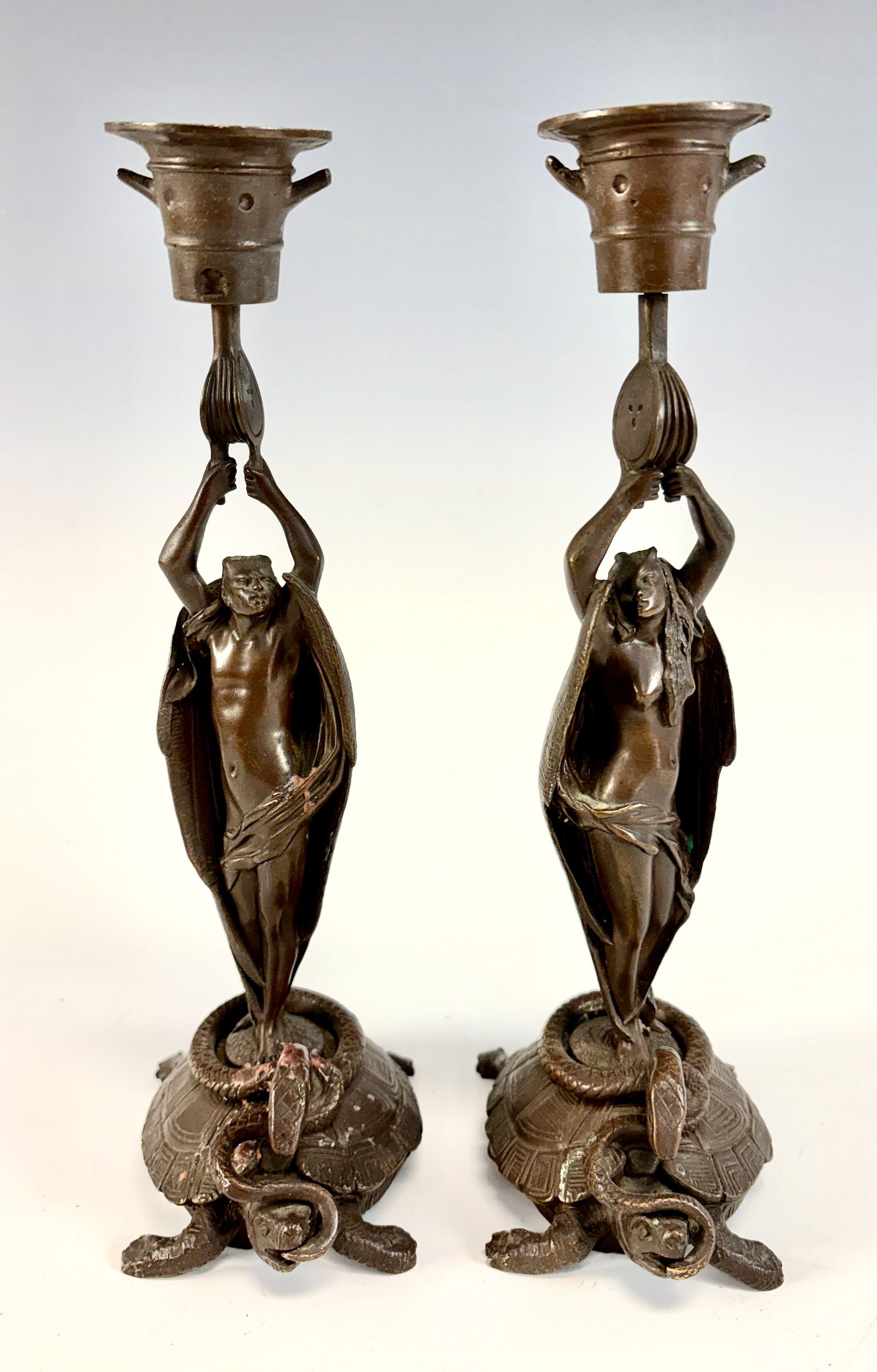 Pair of Bronze “Devil and She-Devil?? Candlesticks: A fabulous pair of 19th-century Symbolist bronze candlesticks depicting a devil and a she-devil, each holding a force bellows supporting a mortar above their heads. They each stand on a base featuring