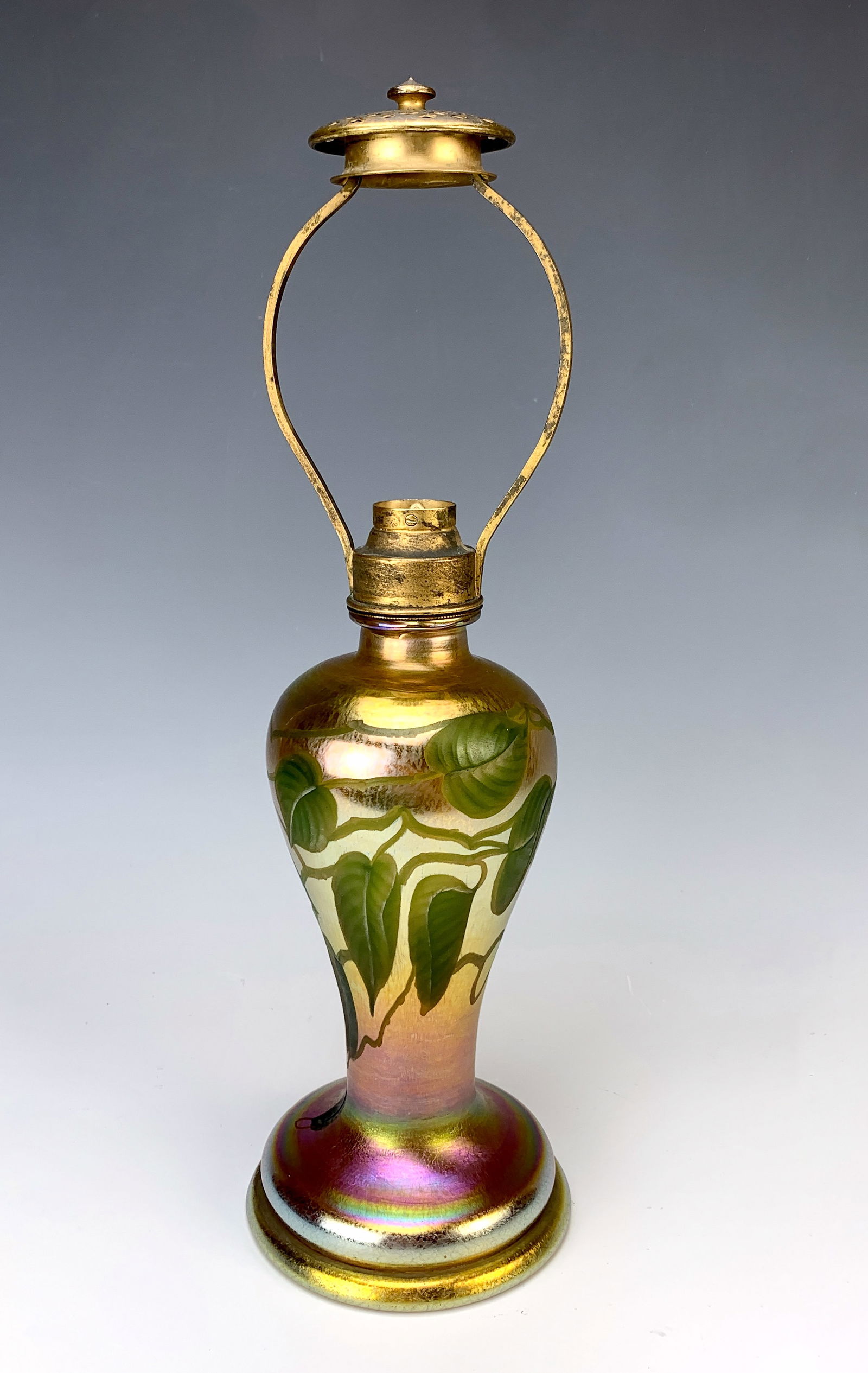 Tiffany Studios Leaf and Vine Favrile Lamp Base: Original signed Tiffany Studios carved leaf and vine lamp base of beautiful gold iridescent Favrile glass featuring green leaves and vines. The glass is signed and in very good condition. Missing sock