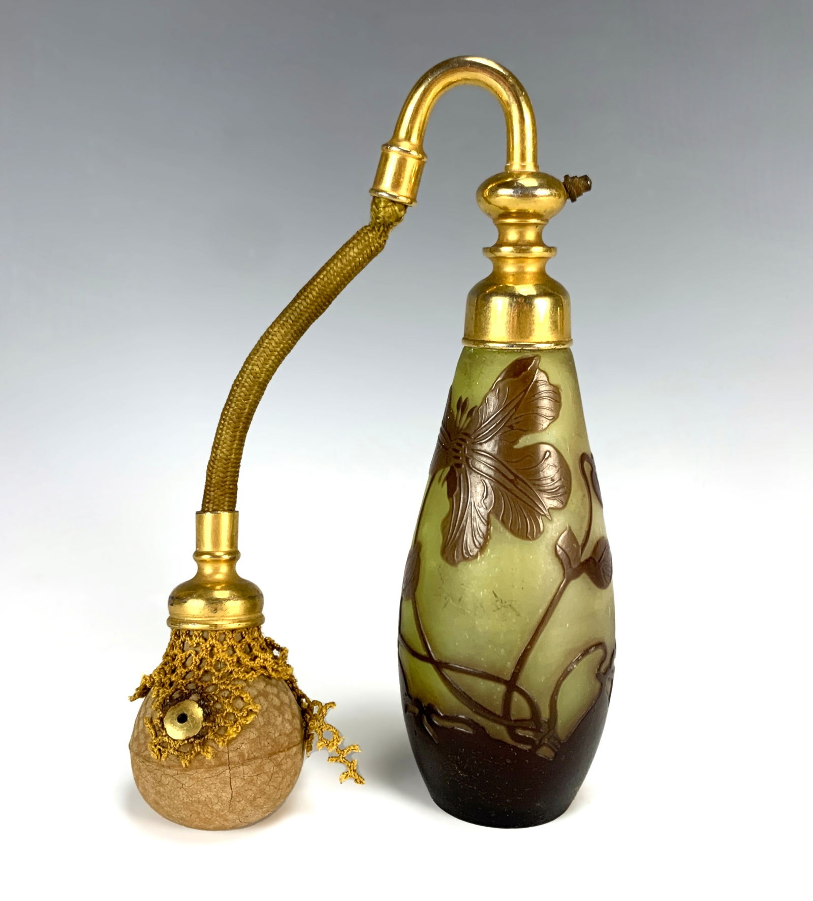 Galle Cameo Glass Perfume Atomizer: Circa 1900. Signed Galle cameo glass perfume atomizer with dark purple cameo flower and leaves against a pale yellow ground. Atomizer gilt metal with bulb. Size: 6.75" tall. Condition: glass good, bul
