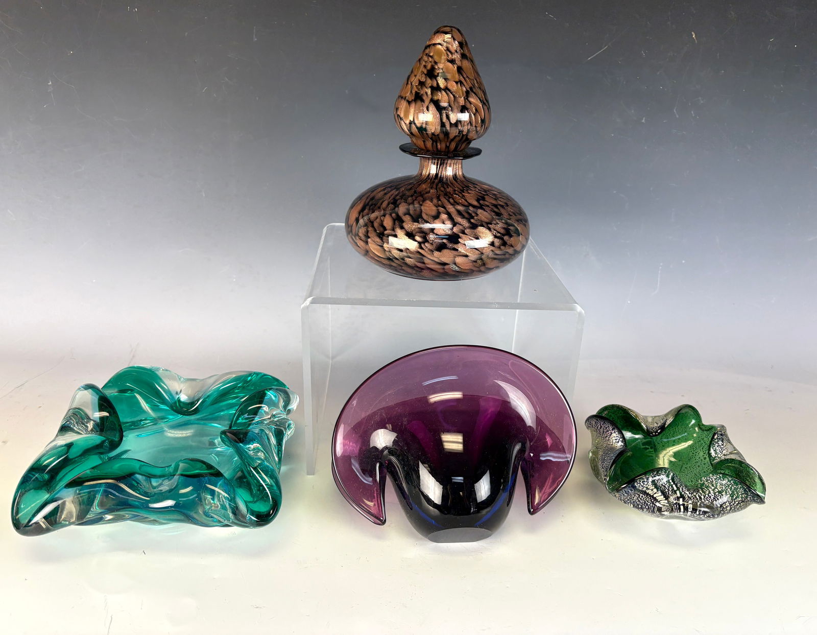 Lot of 4 Vintage Mid Century Murano Glass Items: Collection of four vintage Murano glass items made in Italy consisting of a copper infused vase, a quadrafoil low dish in rich dark leaf green infused with metallic silver bits with curled edges, a