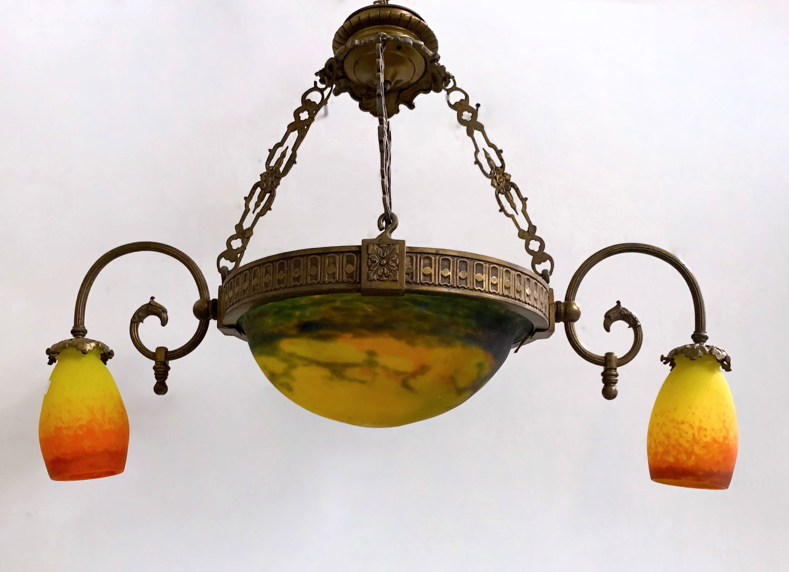 Muller Fres Luneville Art Glass Chandelier: Circa 1920, two-arm chandelier in bronze with three art glass shades, all signed Muller Fres Luneville. The shades are yellow, two smaller shades in yellow with red mottled glass, and the center shade