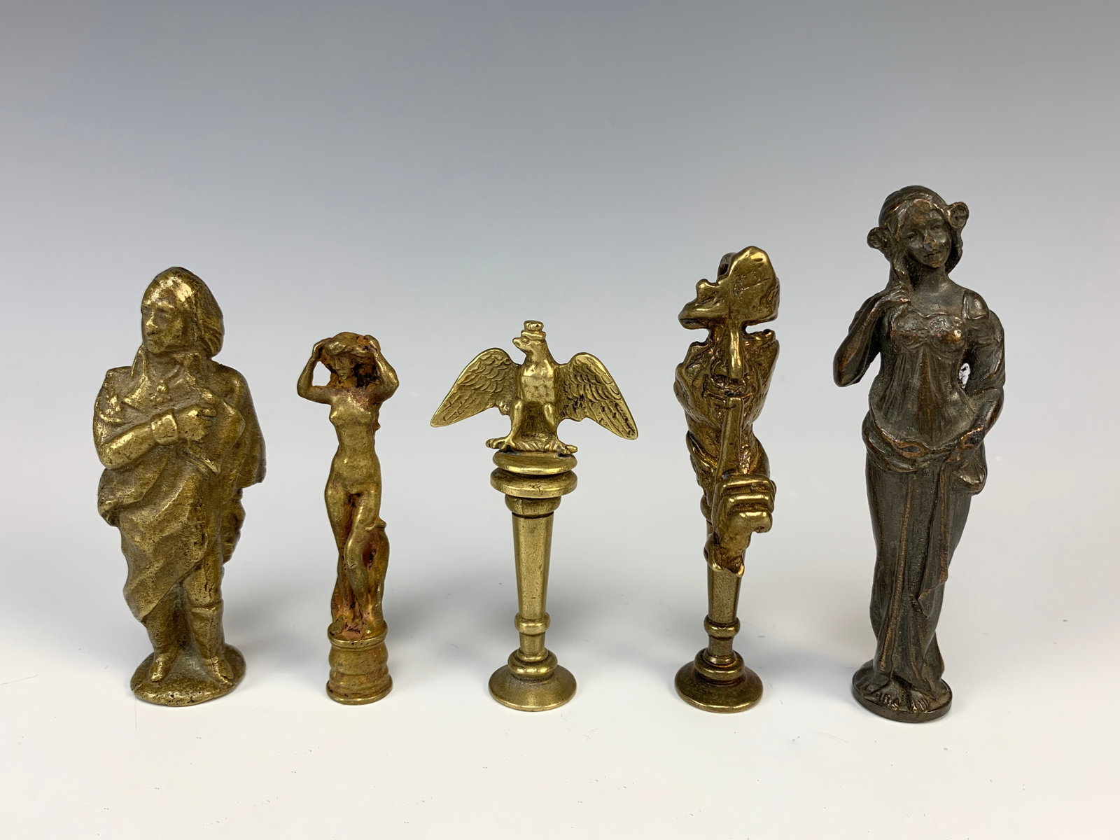 Collection of 5 Bronze Antique Letter Seals: Great collection of bronze letter seals, early 20th C. Included a politician, girl pulling her hair, standing nude, main with finger at his mouth and spread winged eagle. 3.5" tallest, very good