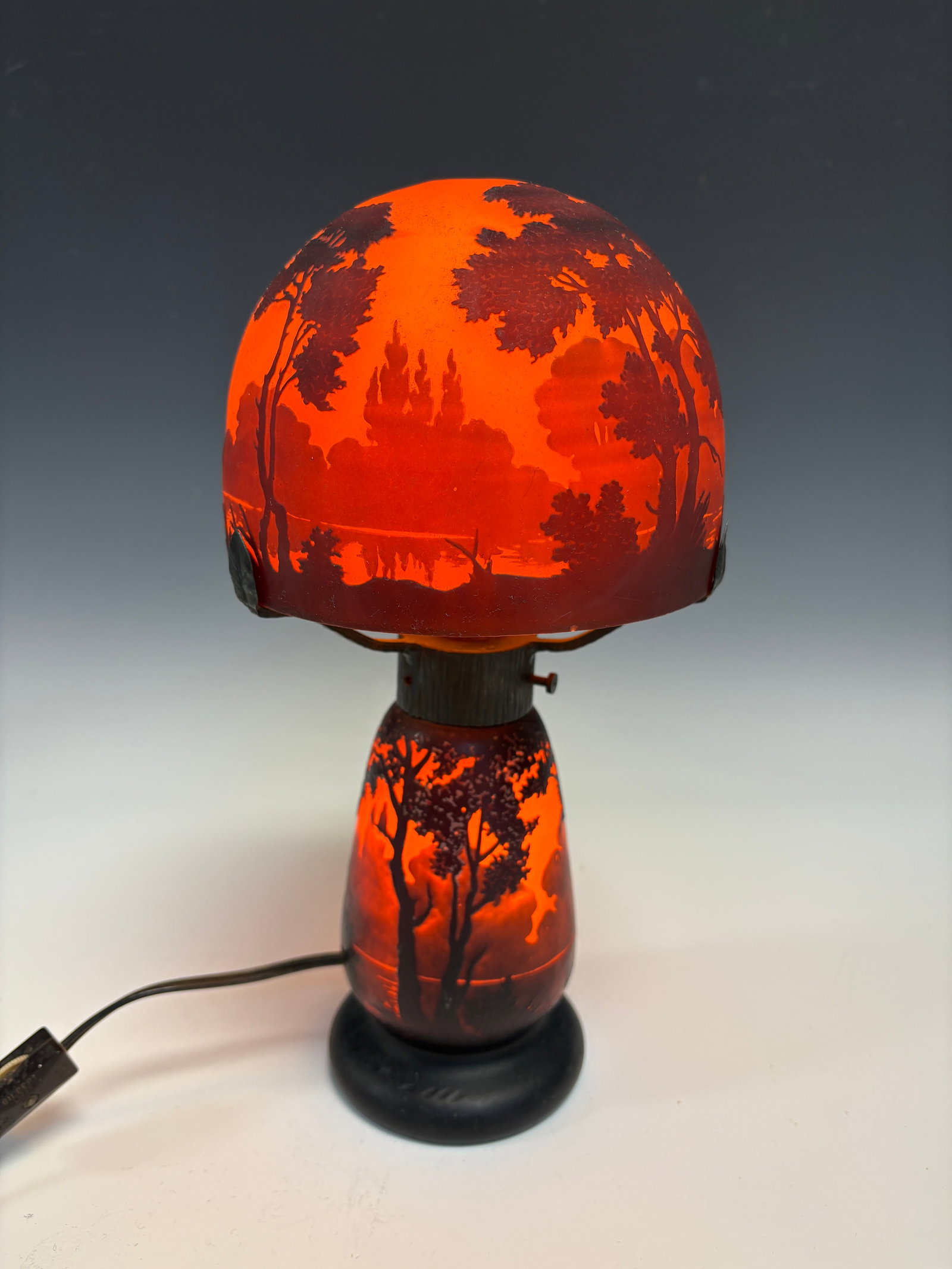 Muller Fres Cameo Glass Lamp: Muller Fres(1895 to 1933) Cameo glass lamp. In two pieces with wrought iron frame supporting a mushroom domed shade depicting a dusk landscape, signed on base and shade Muller Fres Luneville. 12" high