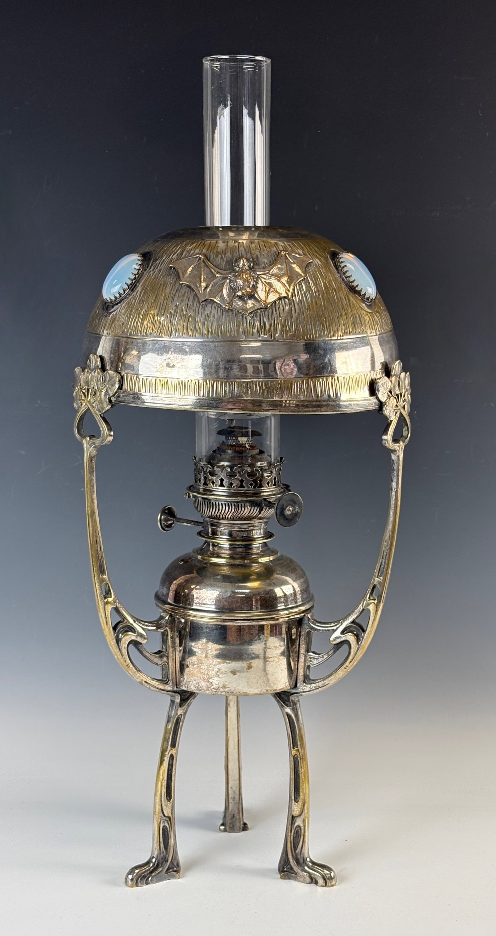 Bat & Jewel Silverplate Oil Lamp Sgd Hugo Leven: Circa 1880, Hugo Leven, a rare and wonderful art nouveau silver plated oil lamp, the domed shade with 3 detailed bats and 3 large opalescent glass jewels, the base with art nouveau lily pads and whipl