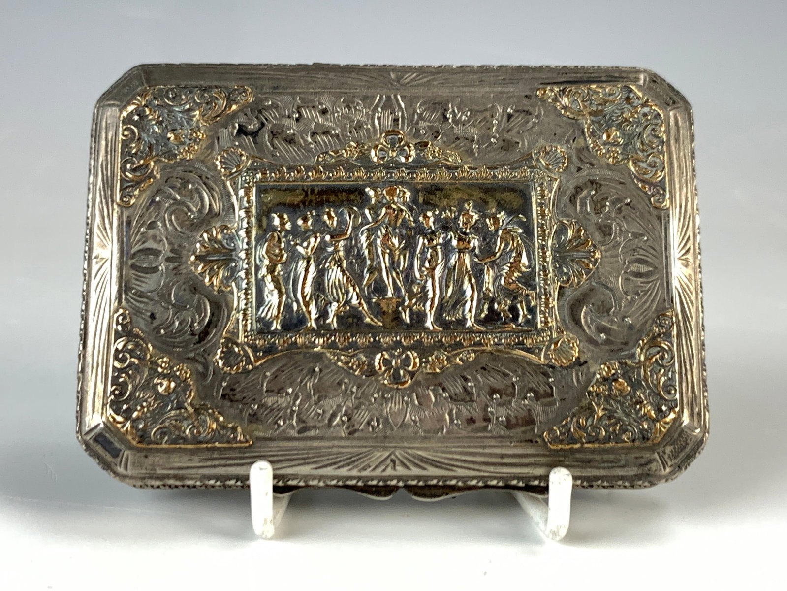 Continental Silver Mixed Metal Snuff Box: Late 19th century. Having a mixed metal continental silver snuff box, the case marked 800, the cover and corners with gold raised dancing figures, good condition, 3" x 2" x 1/2".