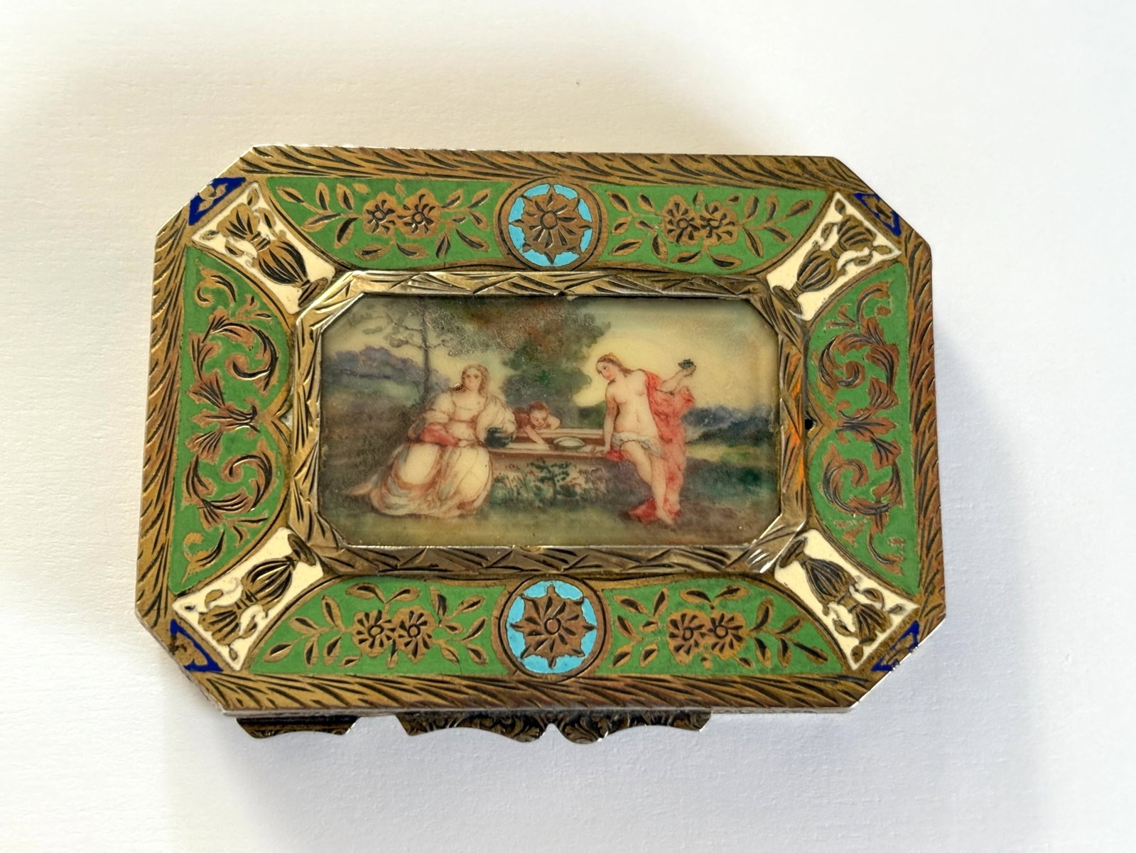 Continental Silver Enamel w Painting Compact: Early 19th Century, a beautiful continental 800 silver compact with elaborate engraving on all sides and the top lid with green, blue and white champleve enamel bordering a central hand painted scen o