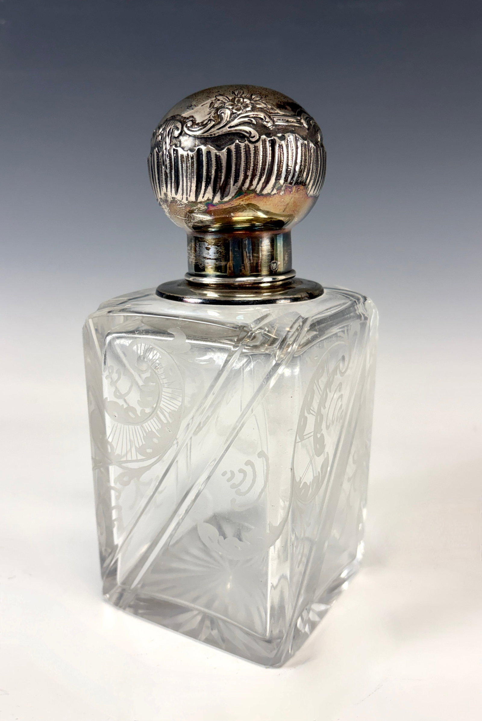 Sterling Silver & Etched Glass Cologne Bottle: Circa 1900, a rectangular crystal cologne bottle with diagonal molded design each side and fancy etched designs, top of bottle with sterling hallmrks and spherical sterling silver lid with sterling