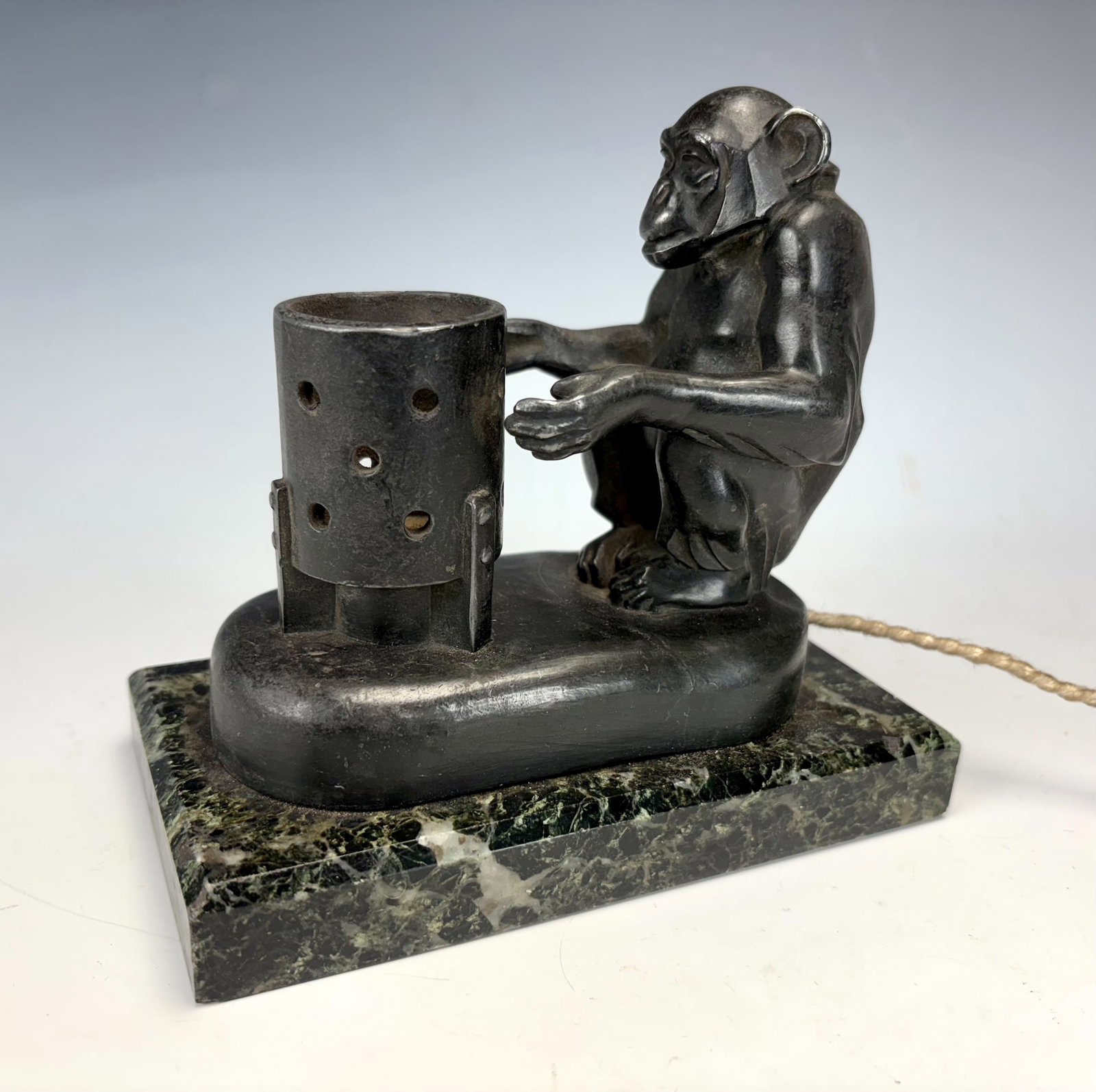 Max LeVerrier Art Deco Monkey Lamp Warming Hands: Circa 1920, Max LeVerrier (1891-1973) a rare art deco figural lamp modeled as a chimpanzee warming his hands by a brazier; the patinated spelter lamp rests atop a veined marble base, signed along base