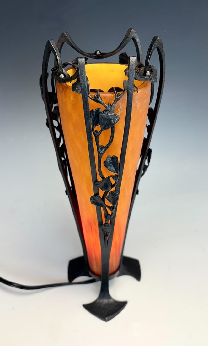 Daum Nancy Art Deco Mottled Glass Iron Lamp: Circa 1920's Conical shaped orange mottled glass lamp surrounded by ornate wrought iron work resting on 3 duck feet. Signed engraved Daum/Nancy with cross of Lorraine. 11.5" tall x 4.5" widest.