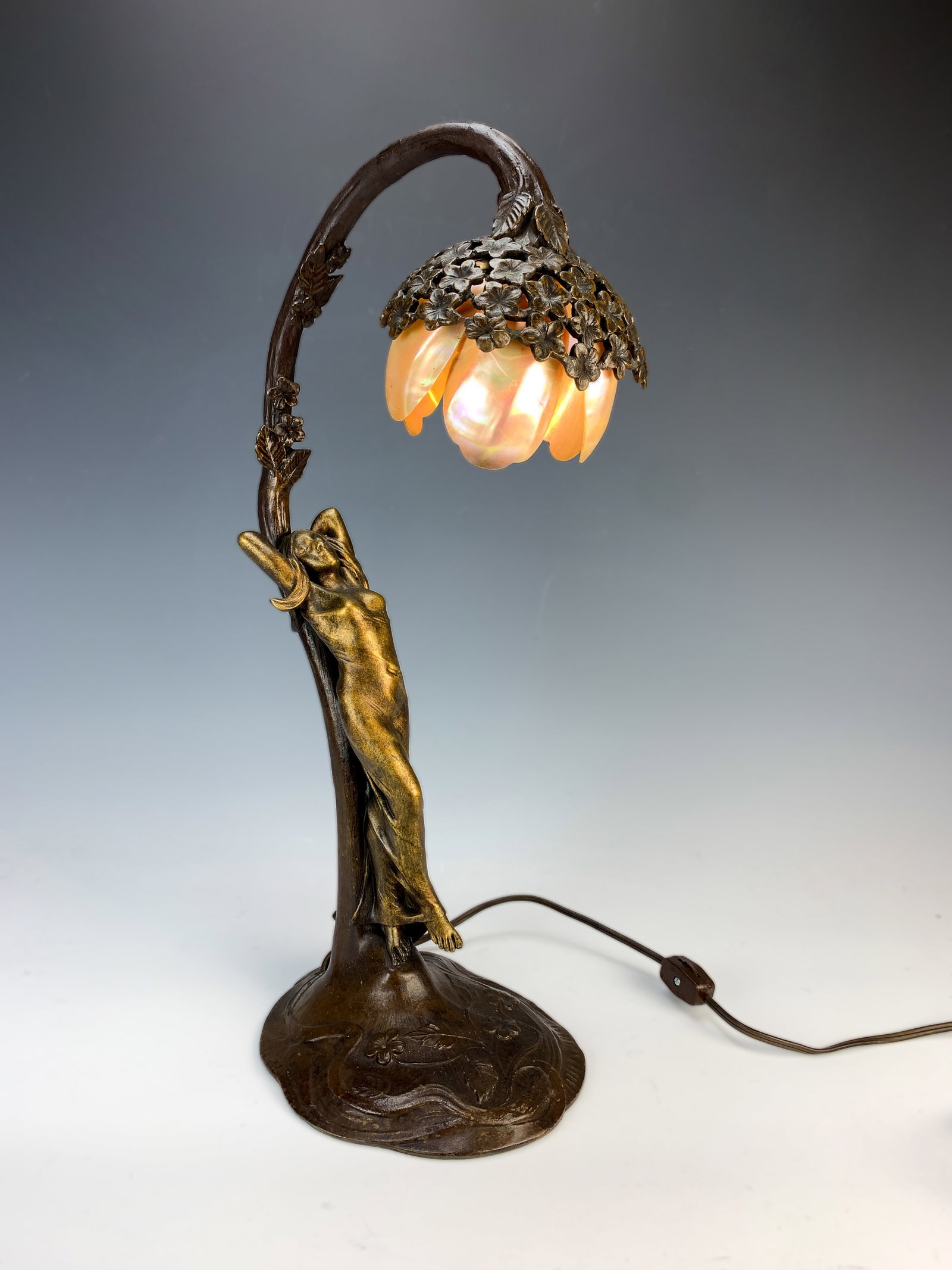Art Nouveau Lady Lamp With Shell Shade Sgd: Circa 1900, figural art nouveau lamp with female leaning against a flowering stem with a mother of pearl petal shade. It is signed on the bottom by R. Elias. good condition, 19" tall.*Electrical warni