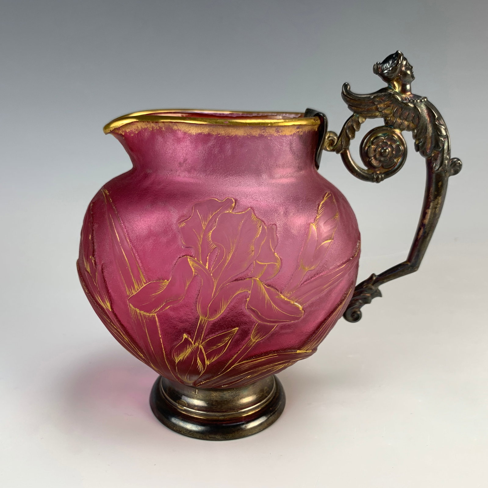 Daum Nancy Cameo Pitcher Figural Silver Handle: Circa 1900, Winged Victory, a fine red cameo art glass pitcher with iris and gilt highlights, sterling silver handle modeled as winged victory figure, hallmarked with the Minerva mark and goldsmith Ed