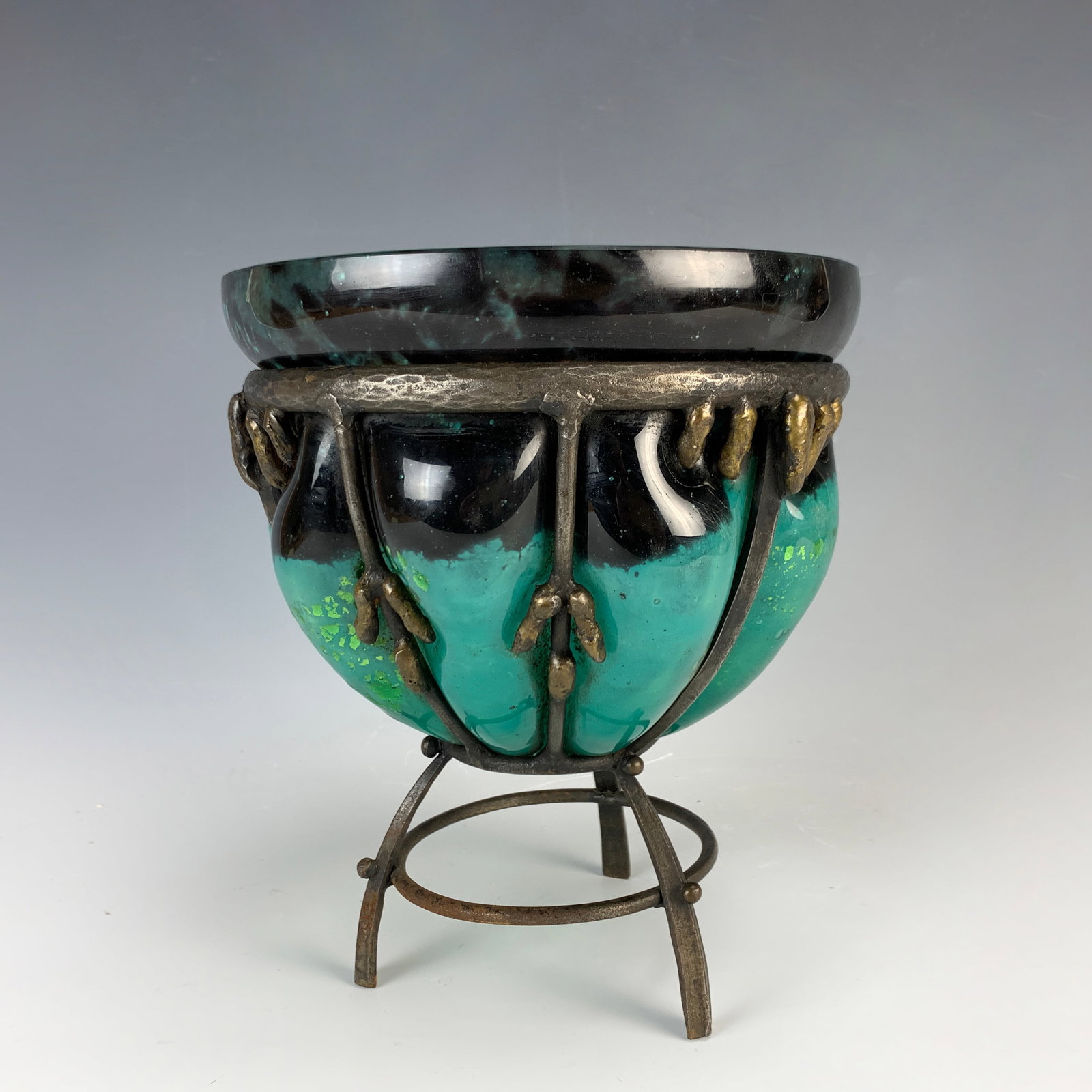Daum Nancy & Louis Majorelle 3-Legged Vase Sgd: Circa 1900 Daum Nancy vase in rare blue green color and black mottled glass with foil inclusions, blown into a Majorelle hammered and patinated iron structure with a tripod base. Signed under the vase
