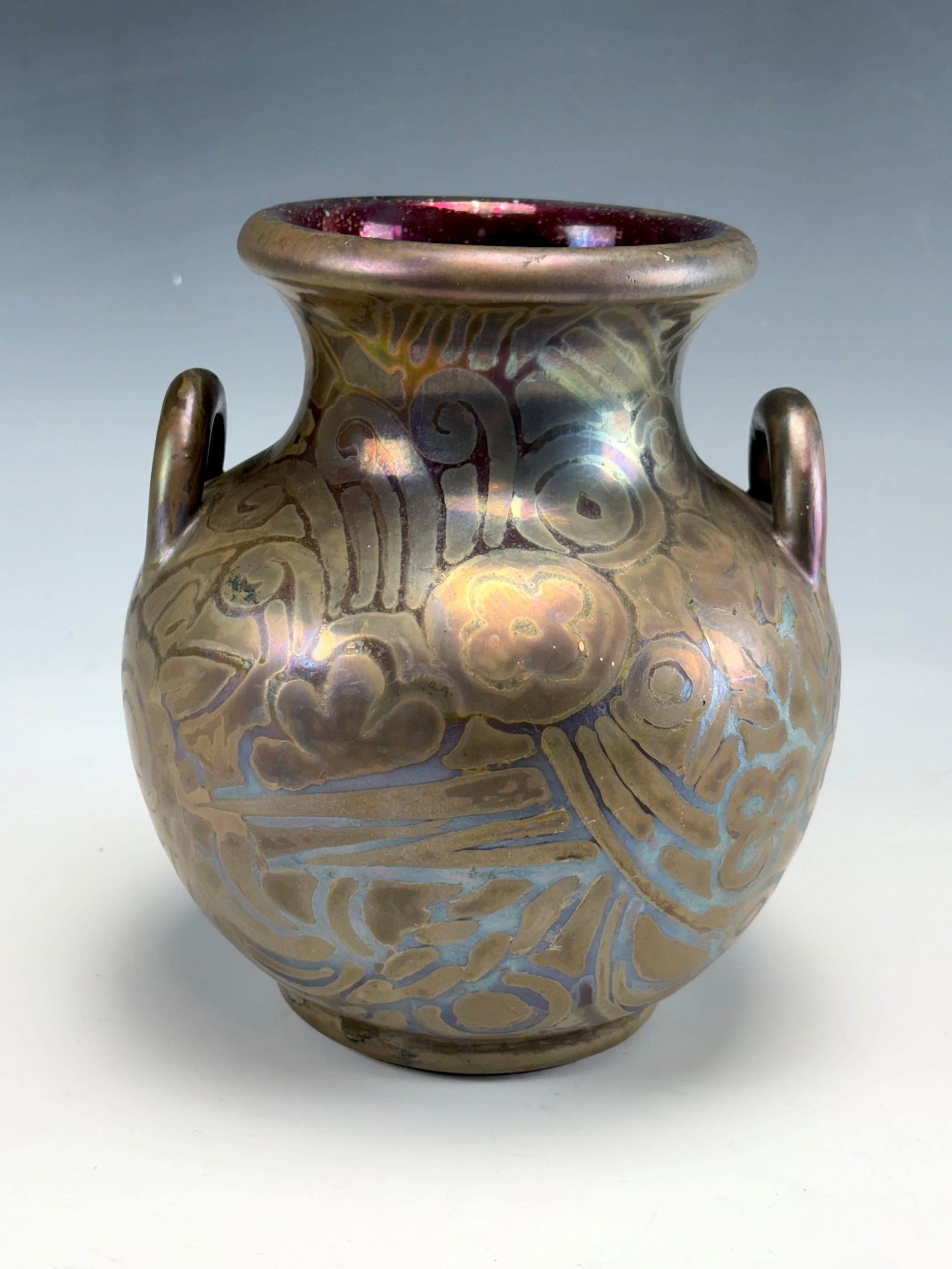 Massier Double Handled Jug Form Vase: Clement Massier (France 1857-1933) An earthenware ceramic double handled vase having a bulbous bottom and a flared top, the red lustre body decorated with silvery iridescent stars and circular designs