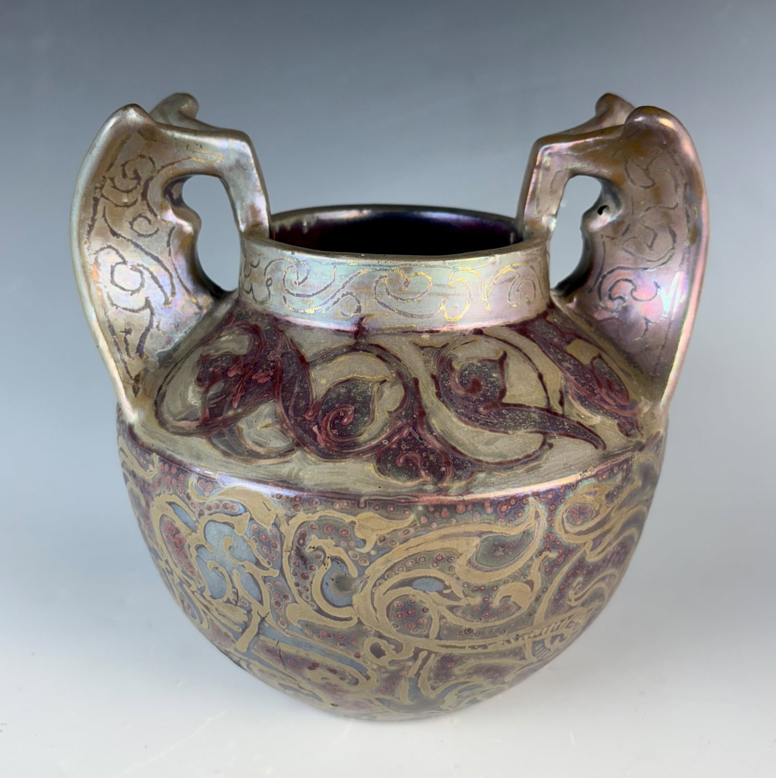 Rare Massier Vase with Stylized Wing Handles: Circa 1900, Clement Massier (French 1844-1917) a rare iridescent ceramic vase with sweeping stylized batwing? handles, decorated overall with intricate swirls and tiny dots in red, violet, silver and 