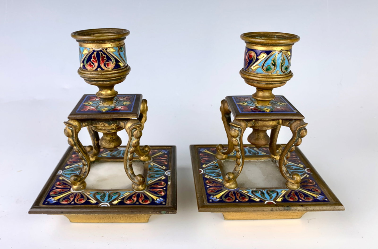 Pair Enamel Gilt Bronze & Onyx Candlesticks: Matched pair of candlesticks having square shaped bases and 4 legs, table shaped French champleve enamel and bronze candlesticks, very good condition, 5" height