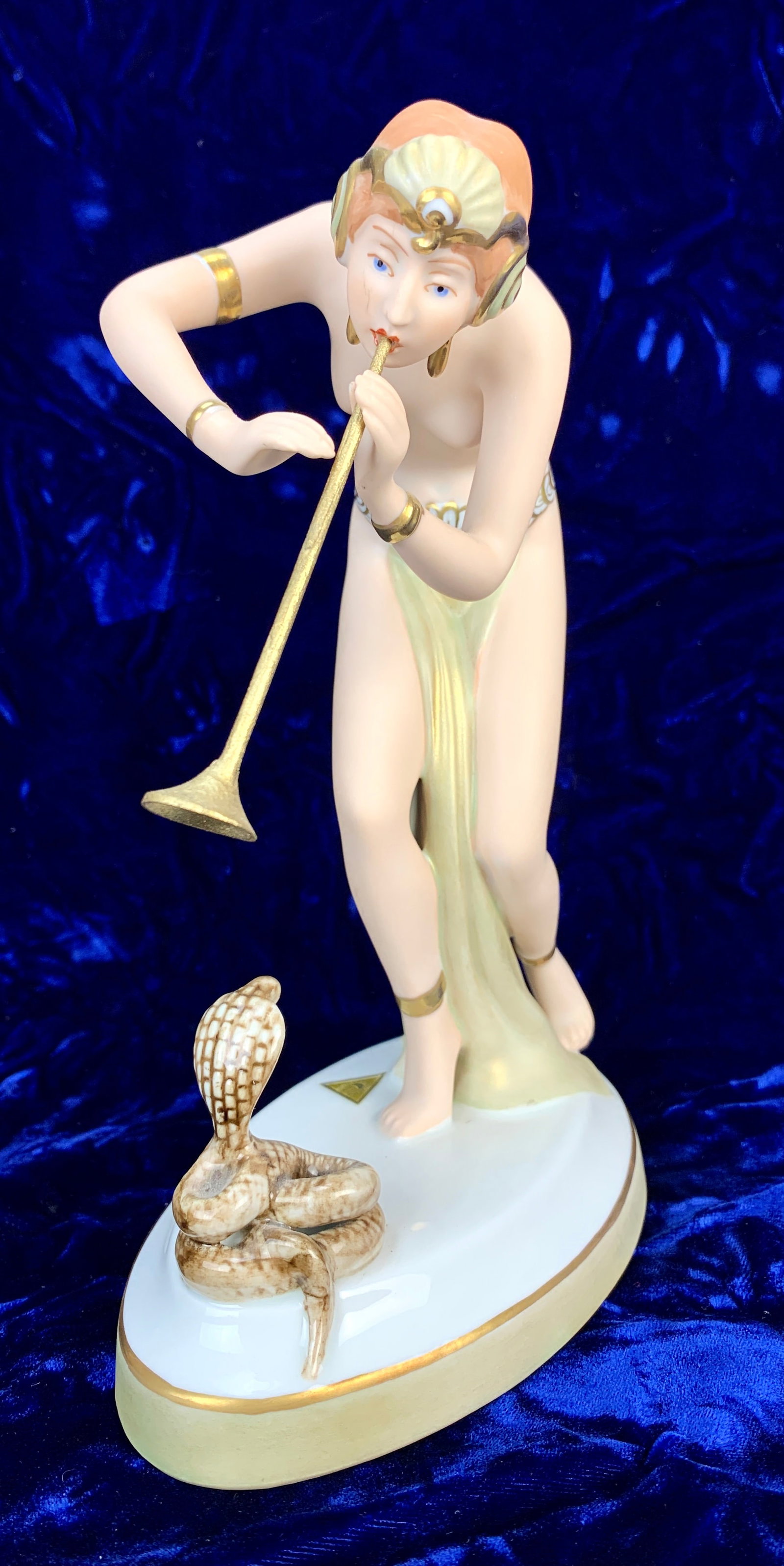 Royal Dux "Lady Snake Charmer": Made of porcelain, depicts a semi naked lady snake charmer. Signed with applied pink triangle. 9" tall. Condition: replaced horn.