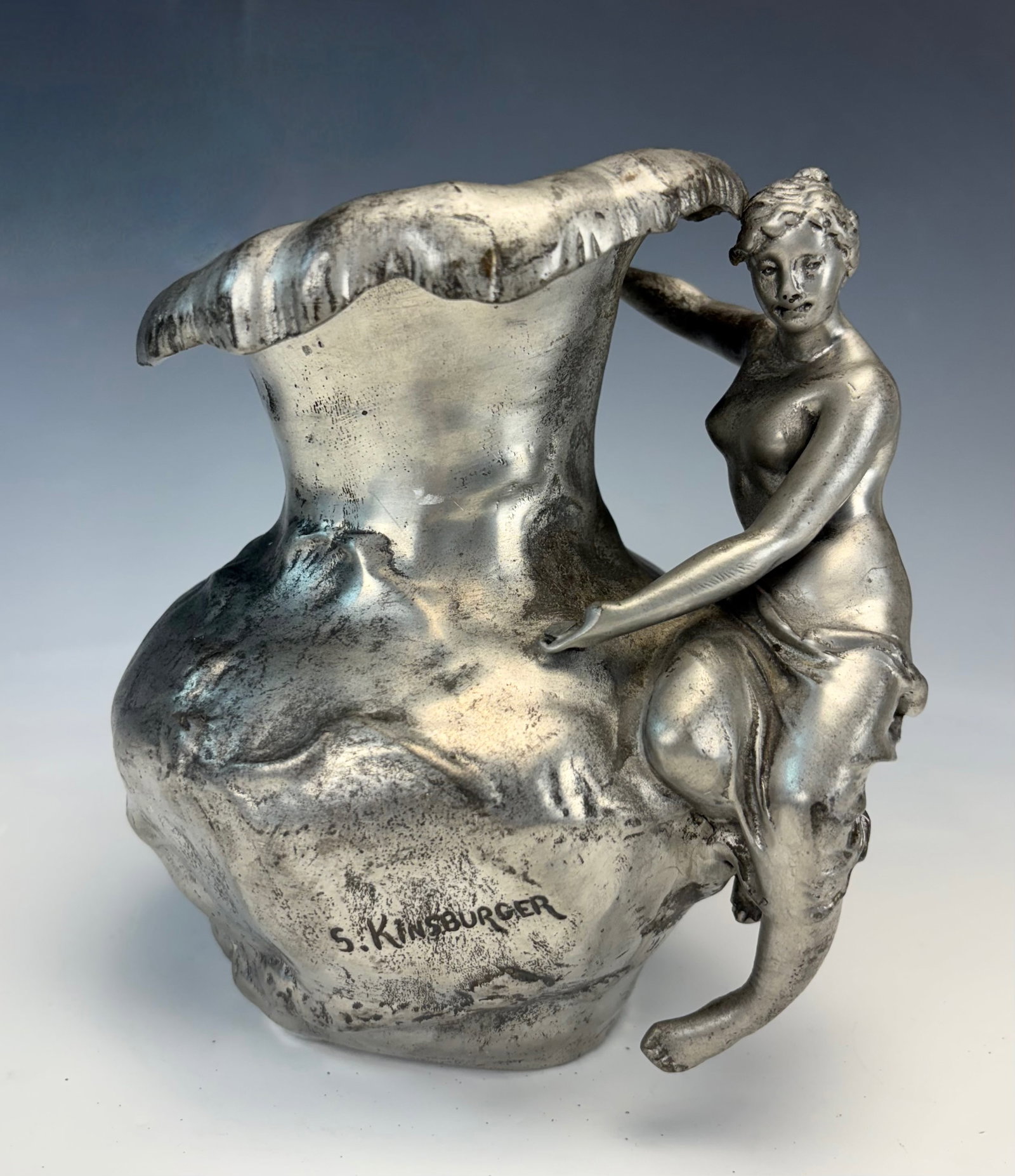 Art Nouveau Pewter Pitcher w Figure sgd Kingburger: Crca 1890, antique pewter pitcher with a semi nude maiden on the shoulder of the base, signed "S. Kingsburger" , 7.25" x 6.5", will not hold liquid due to opening on bottom, good condition