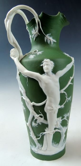 Jasperware Pitcher with Male Nude: Green matte ground with white raised relief figure of a male nude with outstretched arms among pine tree limbs with pinecones. Marked with incised "7964 22" and with stamped mark "Germany". Height 10"
