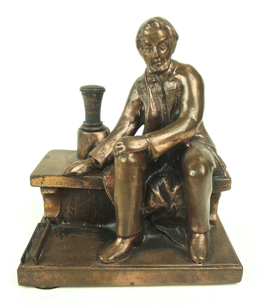 Abraham Lincoln Cigar Lighter: Circa 1900, cigar lighter modeled as a figure of Abe Lincoln sitting on bench alongside the wand, metal with copper finish, height 4.5", good condition