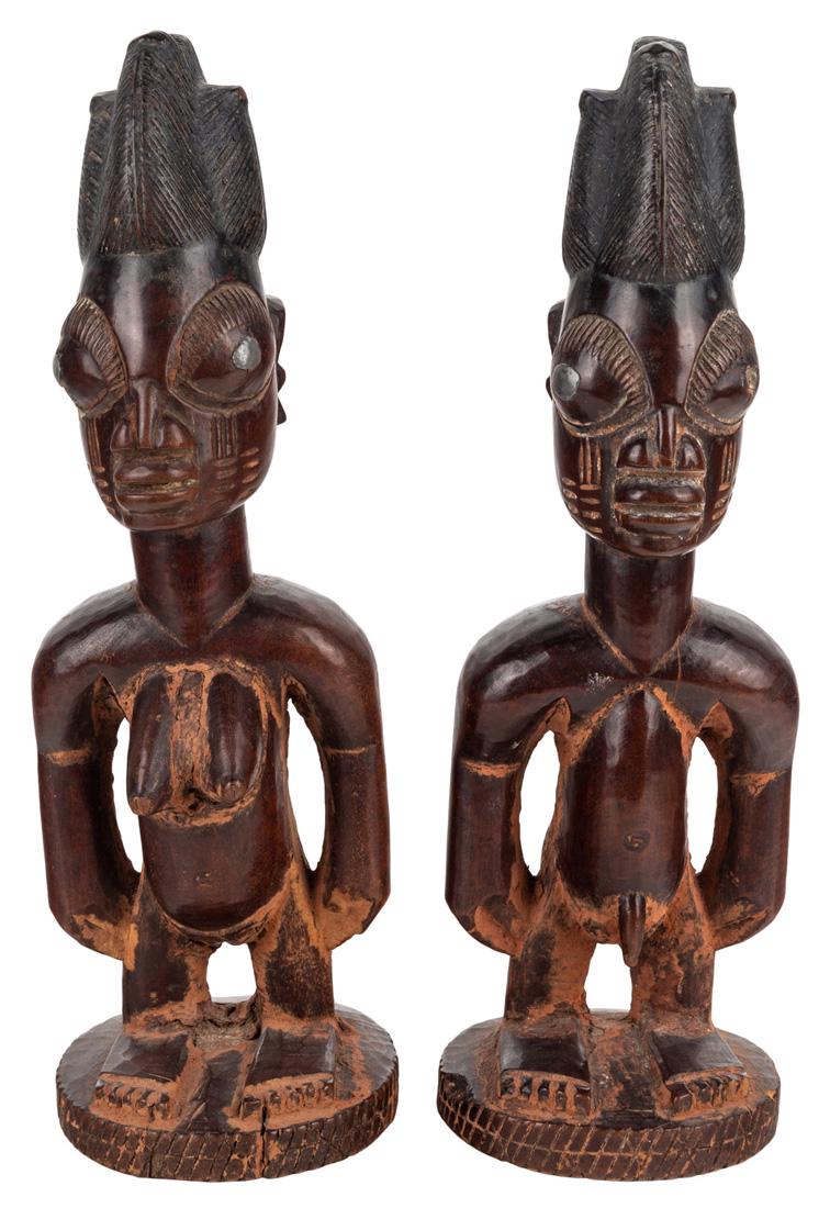 A PAIR OF HARDWOOD YORUBA IBEJI STATUES, NIGERIA: A PAIR OF HARDWOOD YORUBA IBEJI STATUES, NIGERIA the male and female twins in hardwood with red-brown patina, the eyes with metal nails (one from the male twin), shown standing, the hair in a vertical
