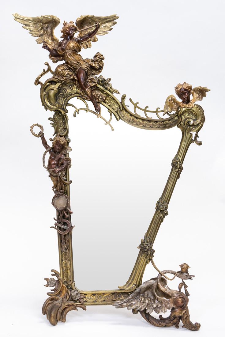 AN ORMOLU BRONZE FRAMED TABLE MIRROR, LATE 19TH CENTURY: AN ORMOLU BRONZE FRAMED TABLE MIRROR, LATE 19TH CENTURY asymmetrical, the frame of rocaille form, depicting a trumpeting angel, head of a cherubim, and another cherubim holding wreath, with suspending