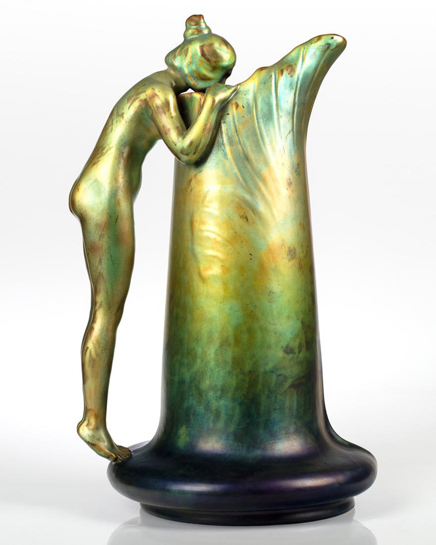 A HUNGARIAN EOSIN-GLAZED EWER 'WOMAN DRINKING FROM: A HUNGARIAN EOSIN-GLAZED EWER 'WOMAN DRINKING FROM FOUNTAIN', ZSOLNAY PORCELAIN FACTORY, PECS, CIRCA 1900 designed by Sandor Apati Abt and Lajos Mack, of slender form with bulbous base, the handle in