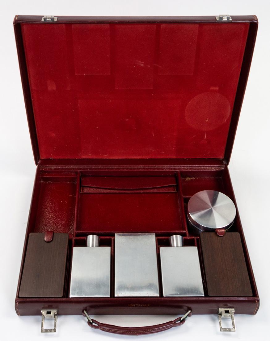 A HERMES MEN'S LEATHER DECO VANITY CASE, CIRCA 1930S: A HERMES MEN'S LEATHER DECO VANITY CASE, CIRCA 1930S claret-red leather with palladium hardware, with sectioned interior, pair of removable trays, pair of hard-bristle brushes, a plastic comb with env