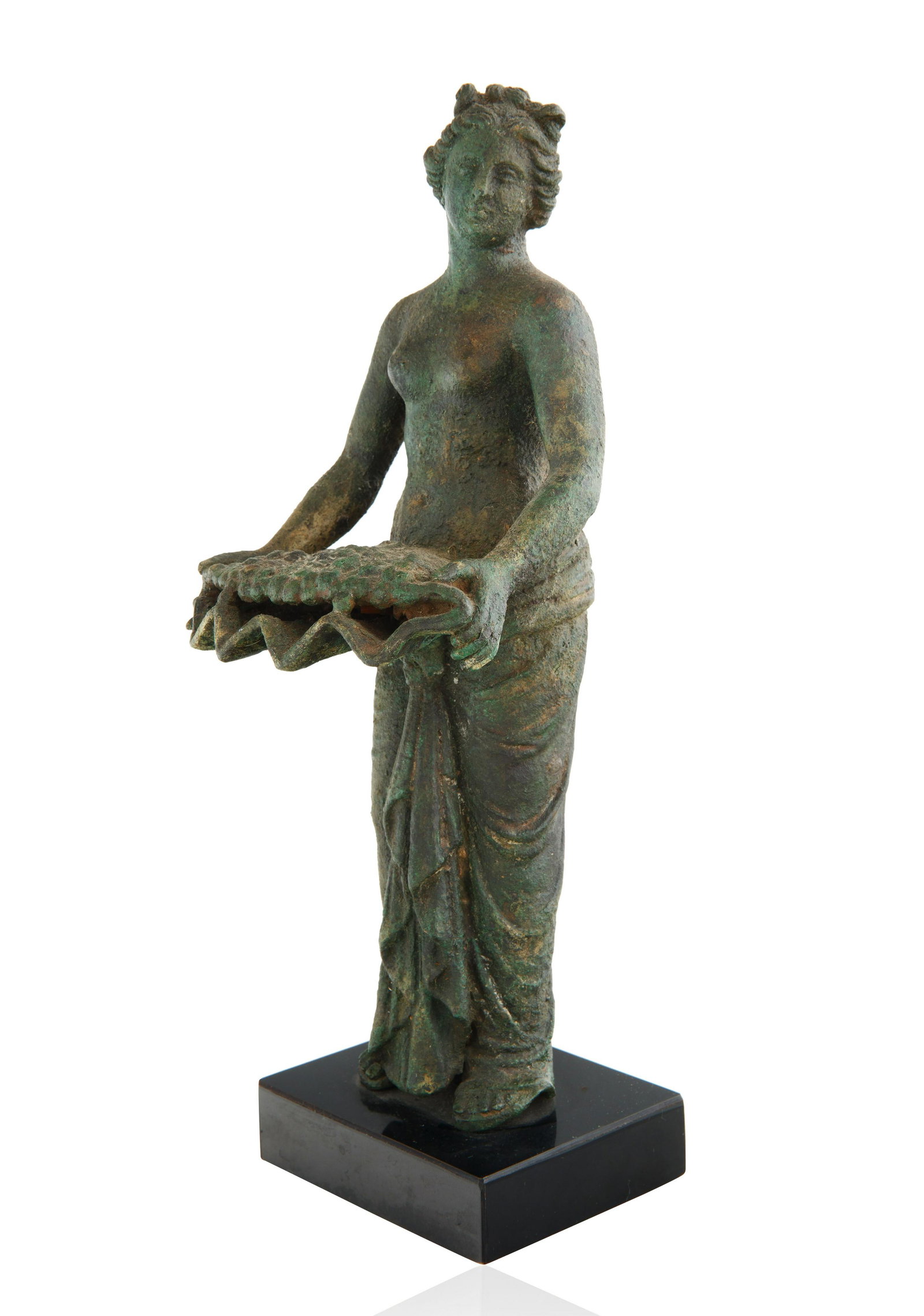 1ST/2ND CENTURY BRONZE ROMAN FIGURE: 1ST/2ND CENTURY BRONZE ROMAN FIGURE modelled in the round, shown standing in three-quarters view, half-nude, holding a scalloped tray of bunches of grapes in both hands, mounted on modern plastic base