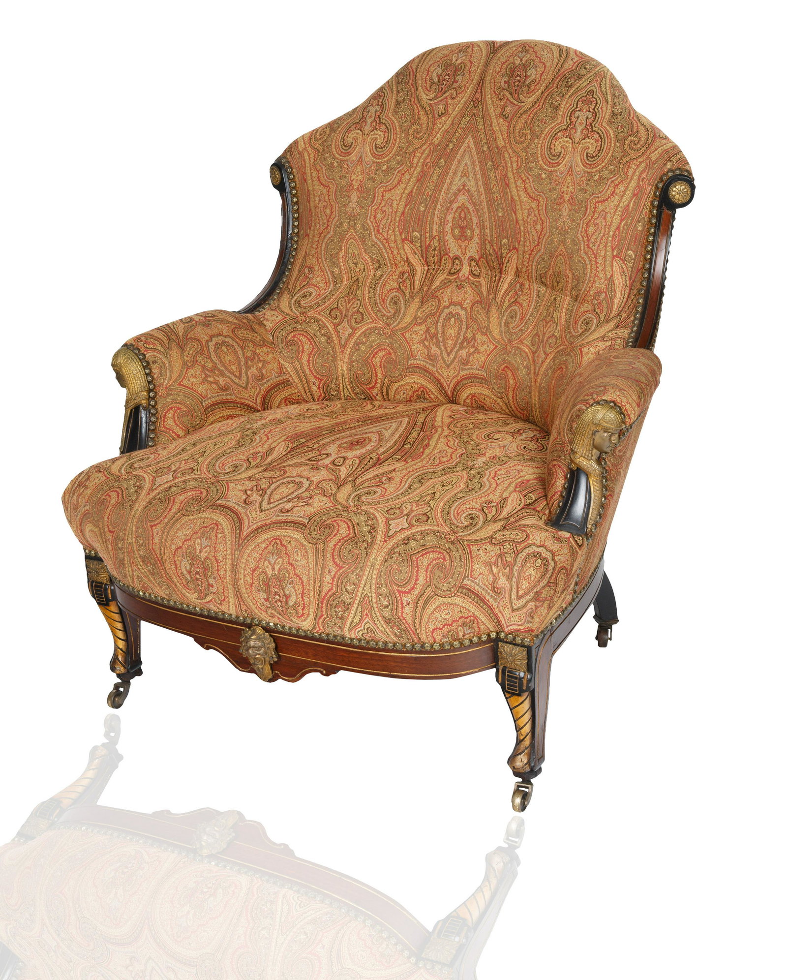 A POTTIER AND STYMUS STYLE UPHOLSTERED ARMCHAIR: A POTTIER AND STYMUS STYLE UPHOLSTERED ARMCHAIR with carved body with upholstered Damask seat, armrests and backrest, the carved body with Egyptian Revival detailing, atop four pin shaped legs with wh