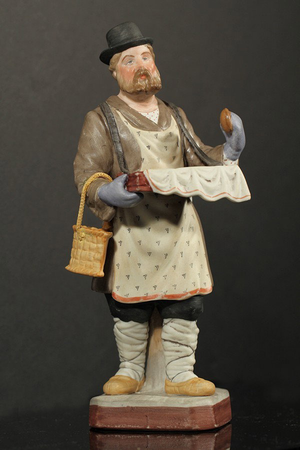RUSSIAN GARDNER PORCELAIN FIGURE: GARDNER PORCELAIN FIGURE OF A MAN SELLING PIROZHKI, Gardner Porcelain Factory, Moscow, figure of a man wearing a hat and carrying a basket selling pirozhki, height: 20.5 cm. (8 in.), red overglazed Ga