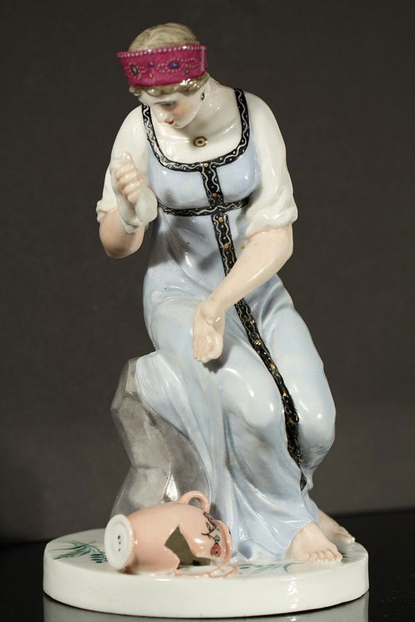 ANTIQUE SOVIET PORCELAIN FIGURE STATE MANUFACTORY: A SOVIET PORCELAIN FIGURE OF A WOMAN WITH A BROKEN JUG, STATE PORCELAIN MANUFACTORY, 1920s, depicting a seated woman in a blue dress holding a handkerchief and weeping over a broken jug, after the 181