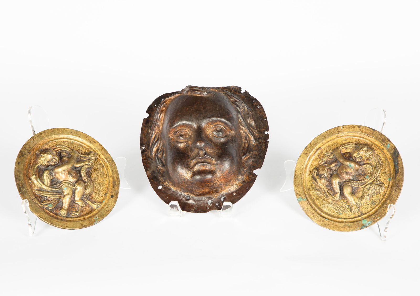 A PAIR OF VINTAGE BRASS PUTTI WALL PLAQUES AND BRONZE MASK OF A CHILD (1 of 3)