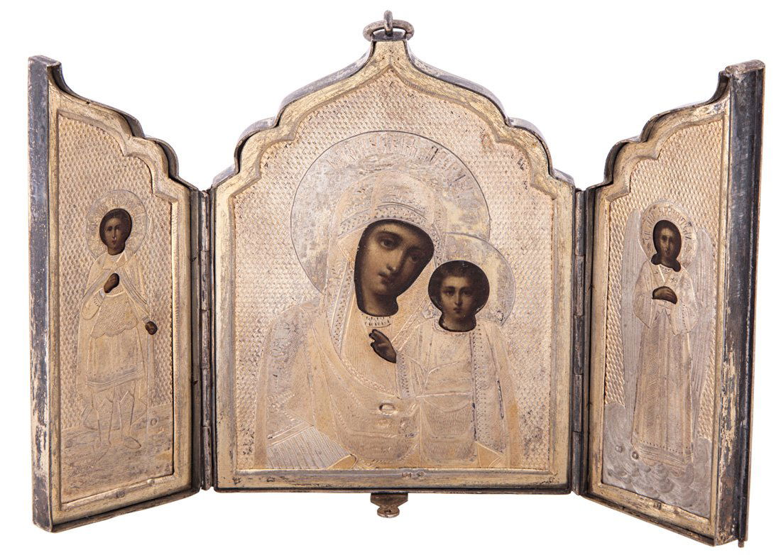 A RUSSIAN GILT SILVER TRAVELING TRIPTYCH ICON, CYRILLIC: A RUSSIAN GILT SILVER TRAVELING TRIPTYCH ICON, CYRILLIC MAKERS MARK SG, 1899-1908, the silver case with a scrolling ivy border and a cross at the closure, the panels open to reveal a central image of