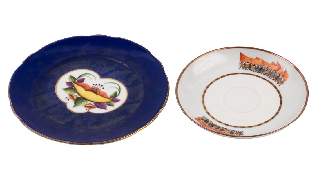 A PAIR OF SOVIET SAUCERS, 1930S: A PAIR OF SOVIET SAUCERS, 1930S comprising: a) Propaganda saucer: the raised upward border painted with Propaganda-themed designs depicting two symmetrically placed groups of people striking For the P