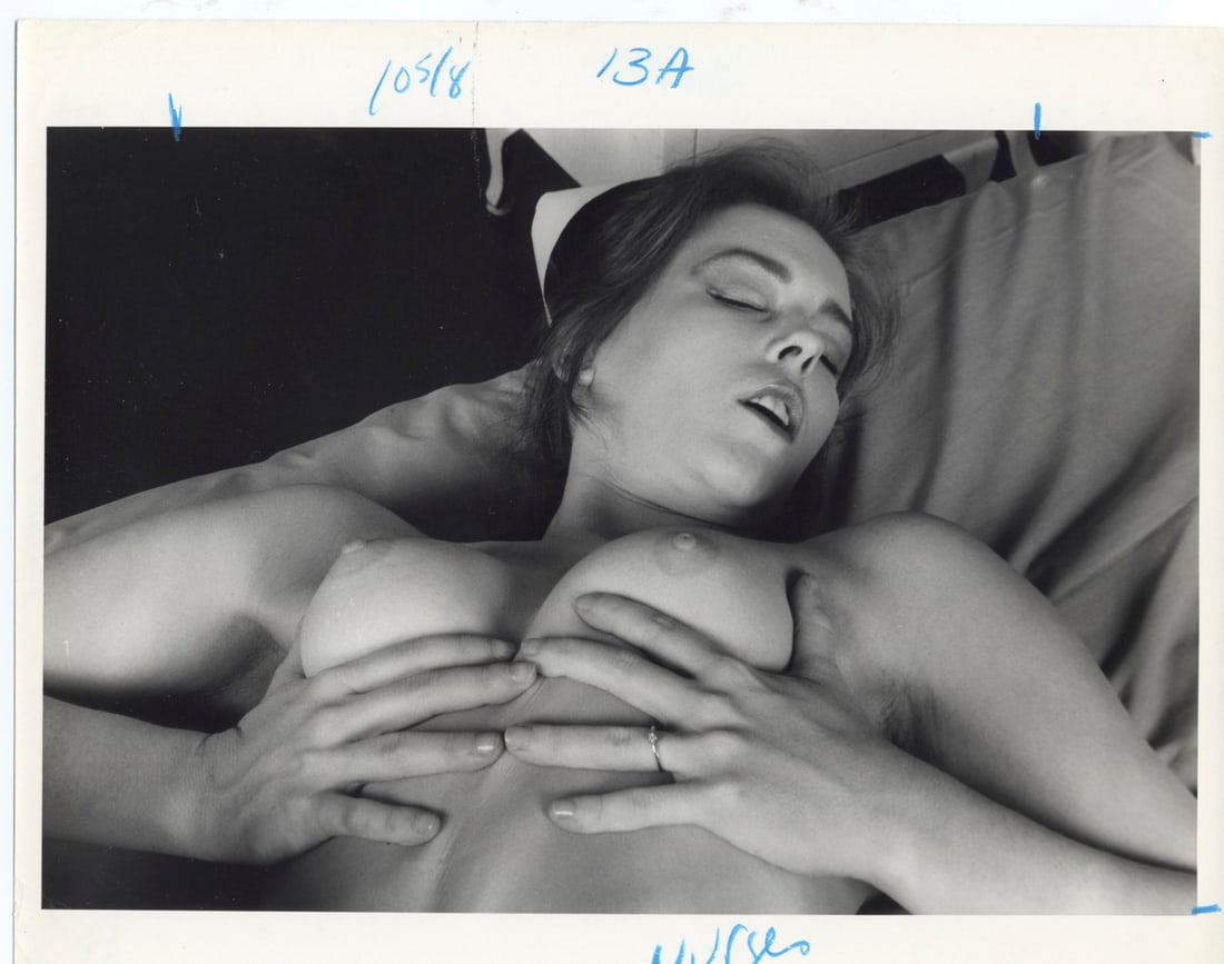 Vintage Artistic Nude Photography: The photograph measures 8 x 10 inches and features a monochrome image of a woman lying on a bed. She is captured from above in a reclined position, with her head turned away from the camera, eyes clos
